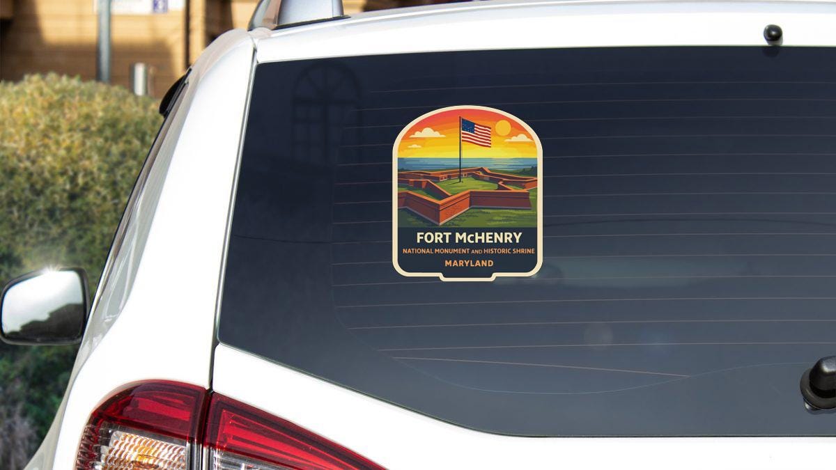 A sticker on the rear window of a white car, depicting a scenic landscape with a flag and text that reads "Fort Mchenry National Monument and Historic Shireine Maryland".