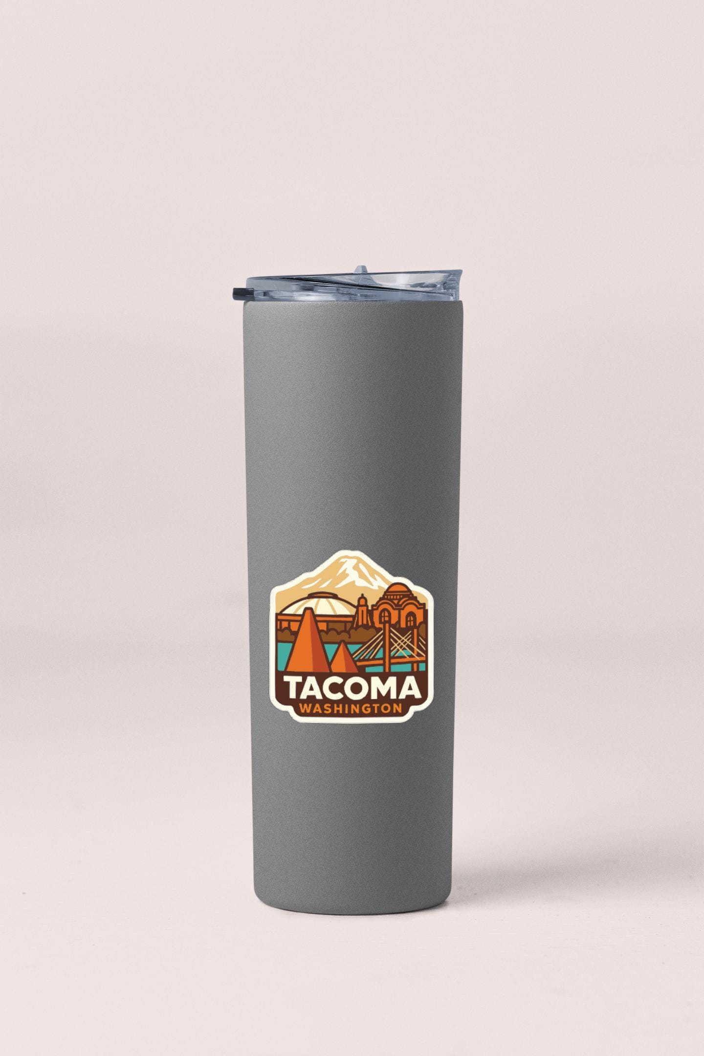 A gray insulated tumbler with a sticker depicting a mountain and the text "TACOMA WASHINGTON" printed on it.