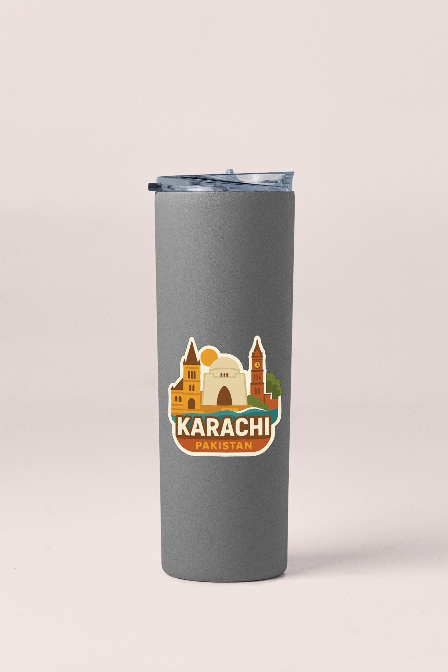 A gray tumbler with a sticker depicting the skyline of Karachi, Pakistan.
