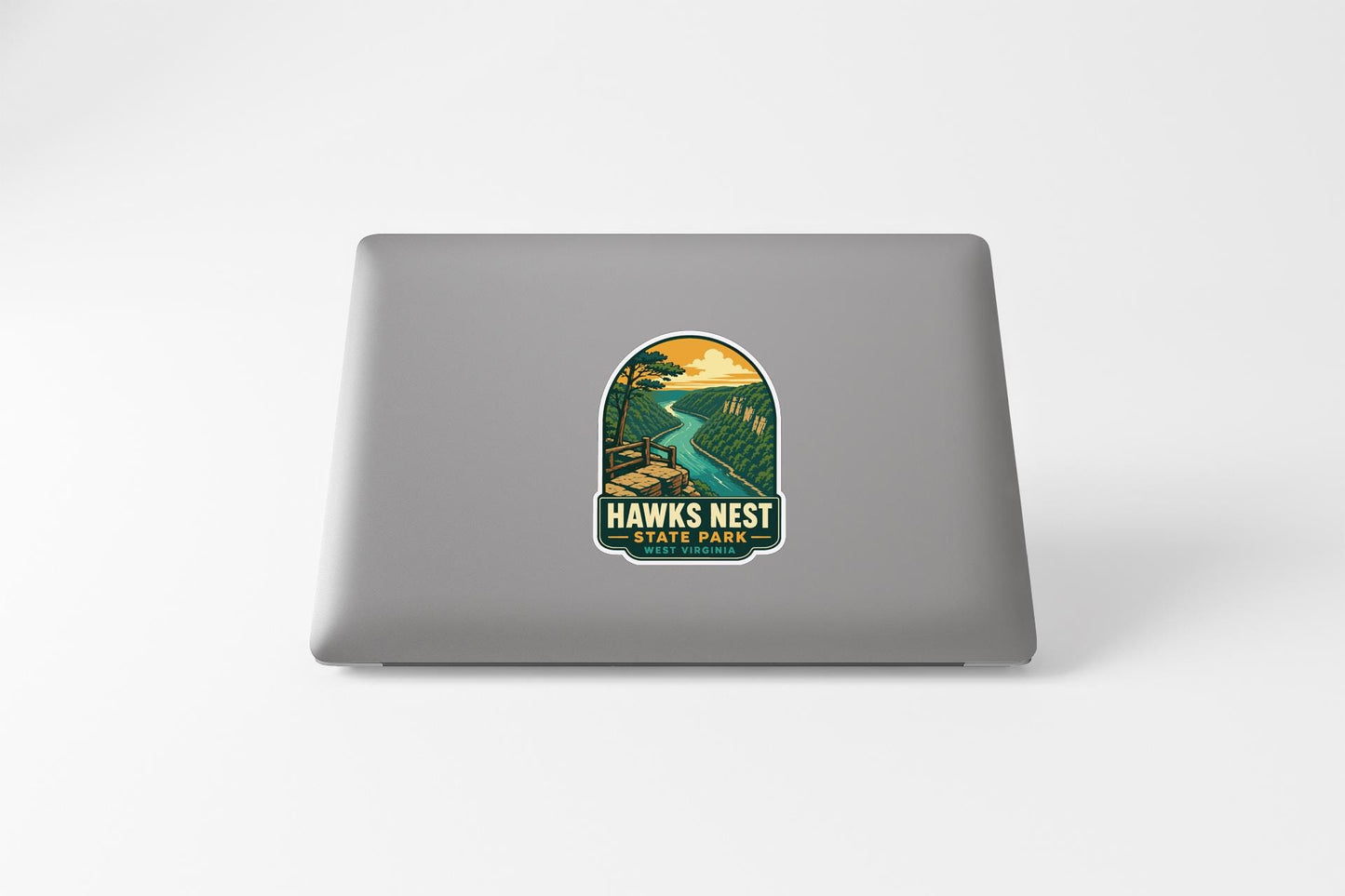 A sticker on the back of a laptop, depicting a scenic landscape with a river and mountains.