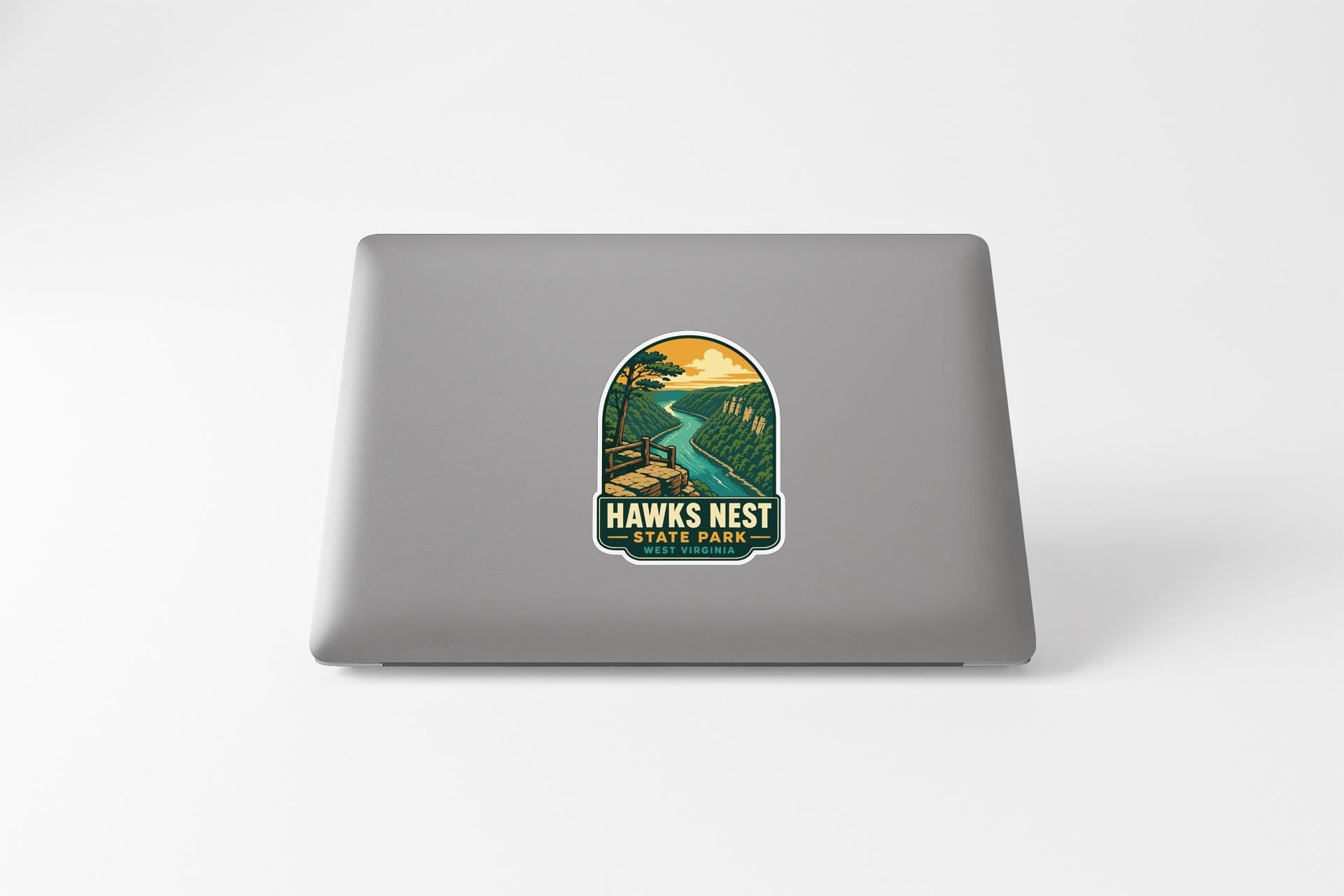 A sticker on the back of a laptop, depicting a scenic landscape with a river and mountains.