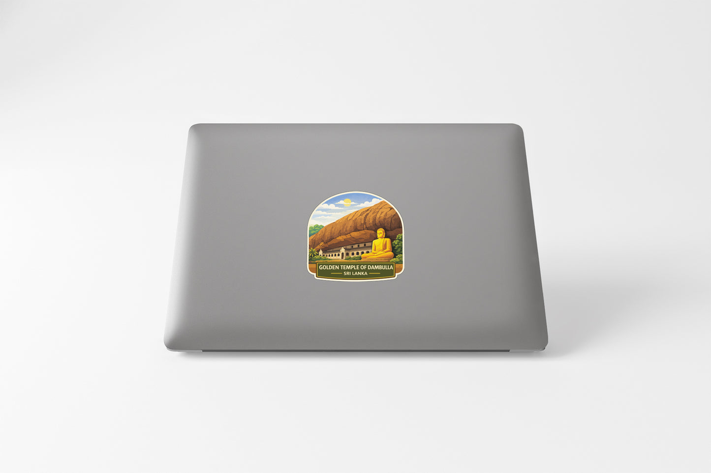 A sticker depicting a golden Buddha statue in front of a mountain landscape on the back of a laptop computer.