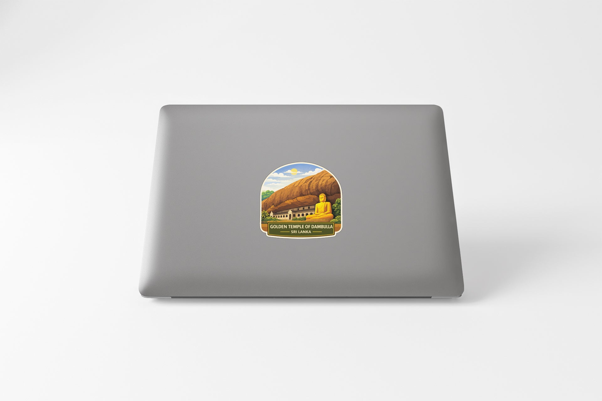 A sticker depicting a golden Buddha statue in front of a mountain landscape on the back of a laptop computer.