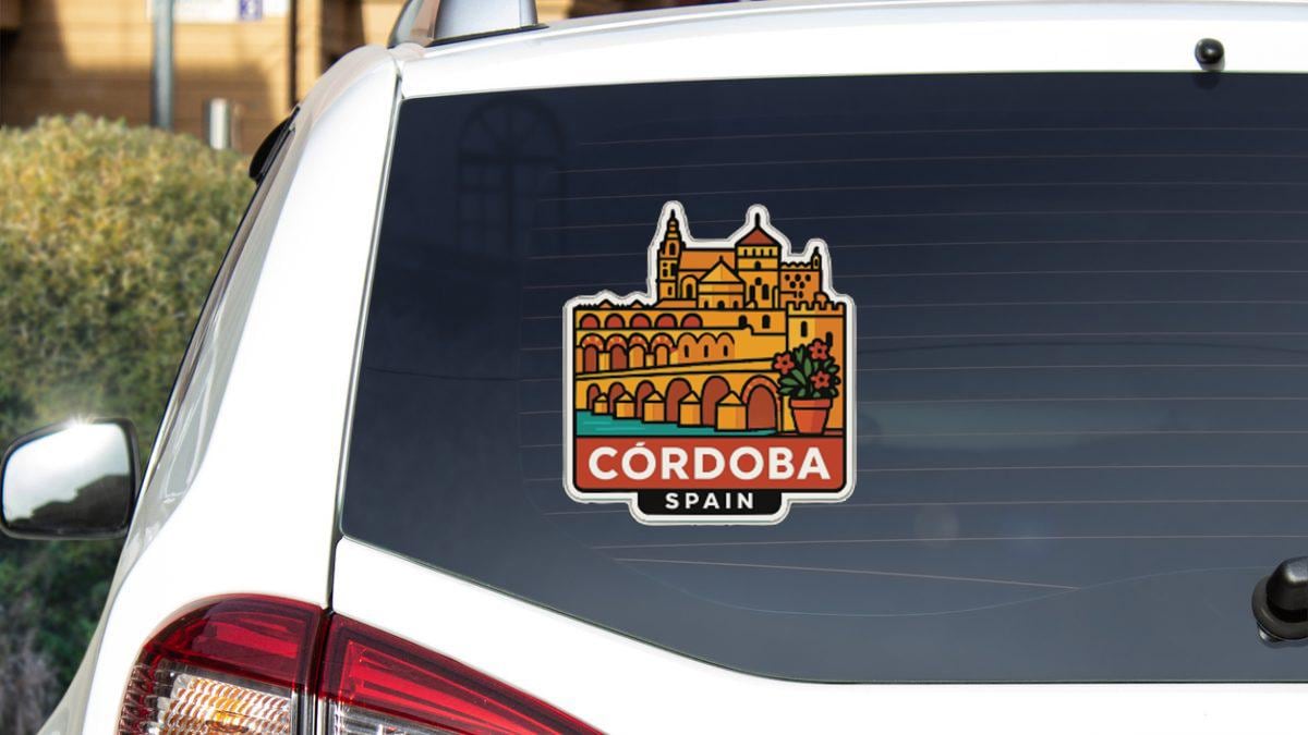 a sticker on the rear window of a white car, depicting a castle or palace-like structure with arches and a tower.