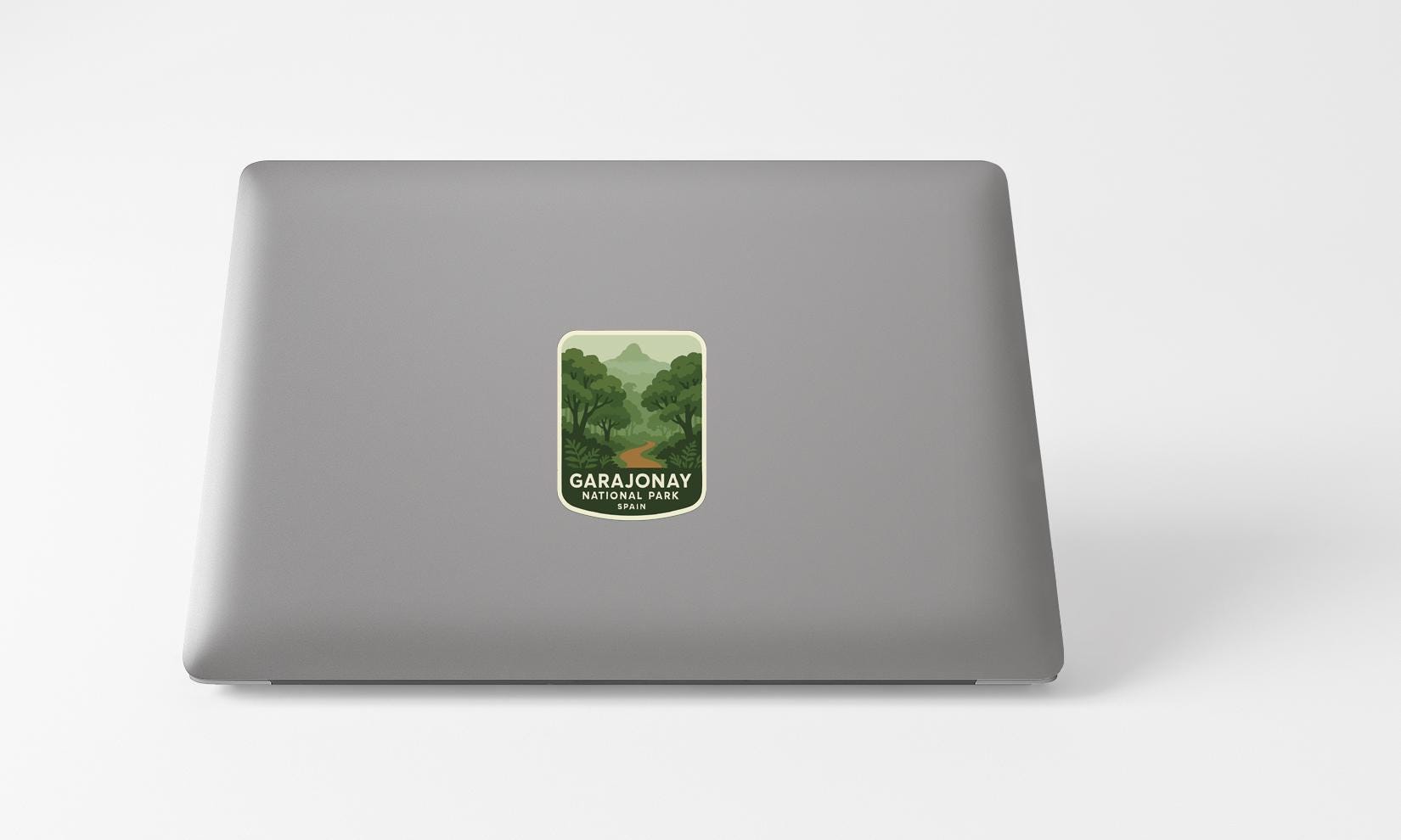 A sticker with a green landscape and mountains on a grey laptop.