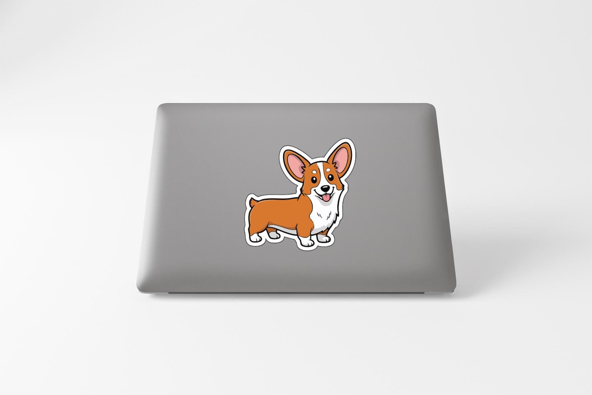 A sticker of a cartoon corgi dog is placed on the back of a laptop computer.