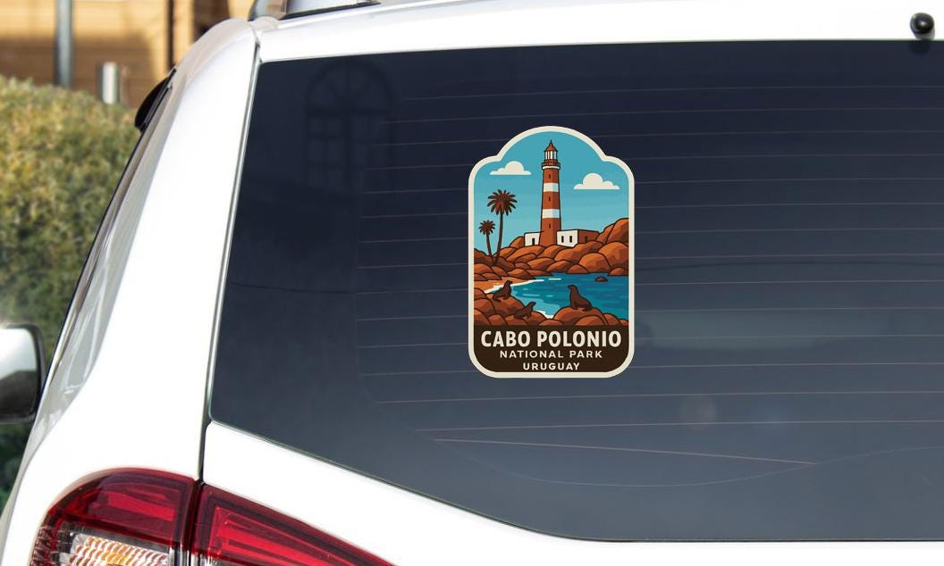 a sticker on the rear window of a car, depicting a lighthouse and a coastal landscape.