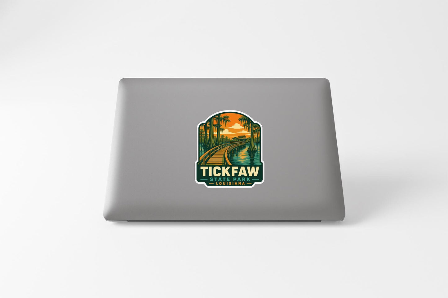 A sticker on the back of a laptop, depicting a scenic landscape with a train track and palm trees.