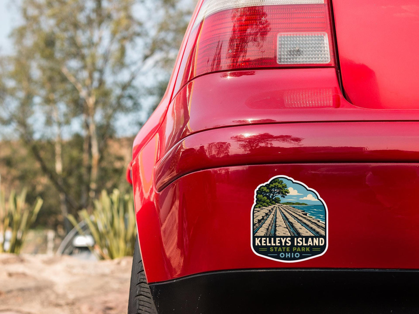 the rear end of a red car with a sticker on the trunk that says "Kelley's Island State Park, Ohio".