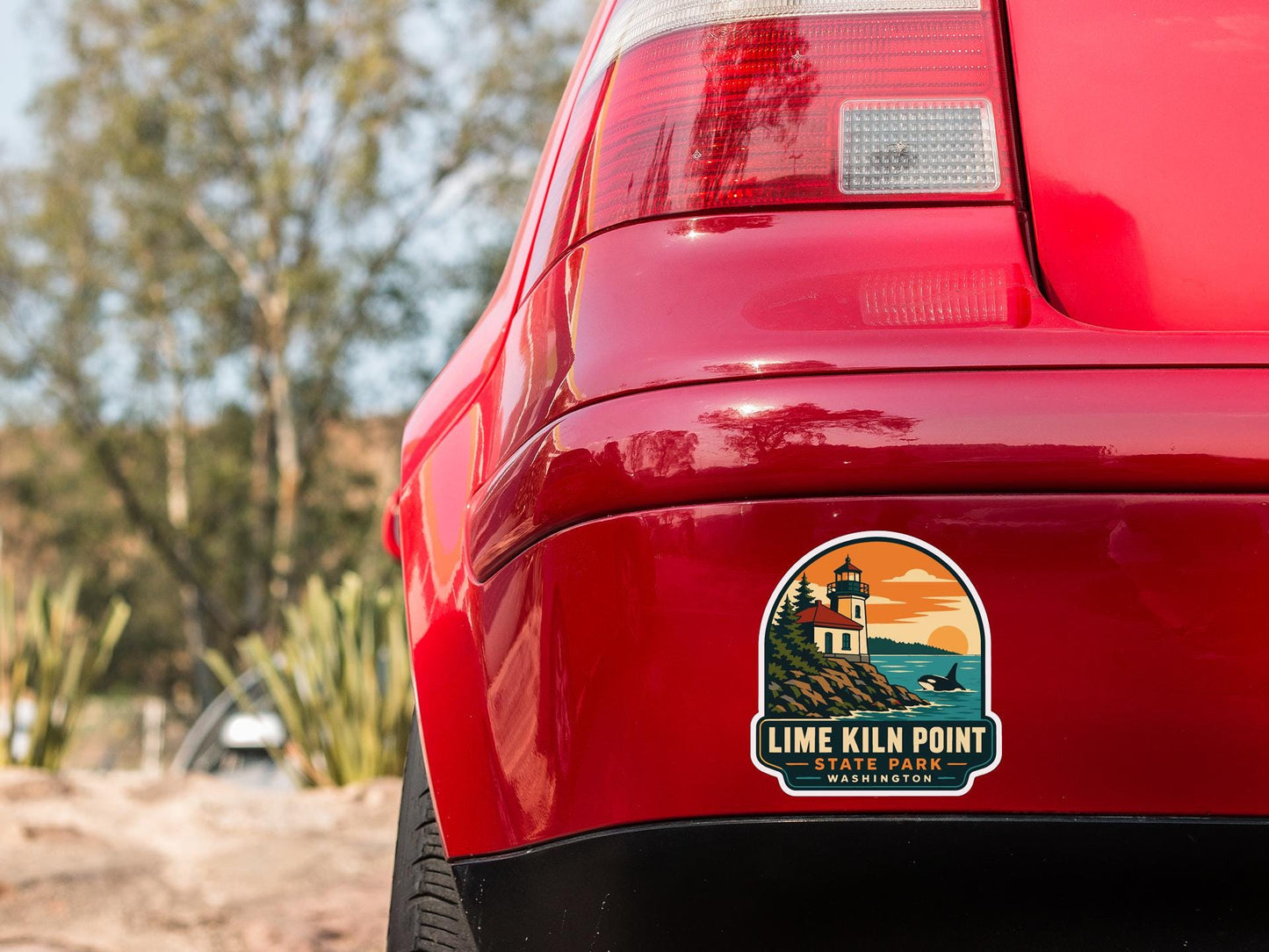 the rear end of a red car with a sticker on the trunk that reads "LIME KILM POINT STATE PARK WASHINGTON".