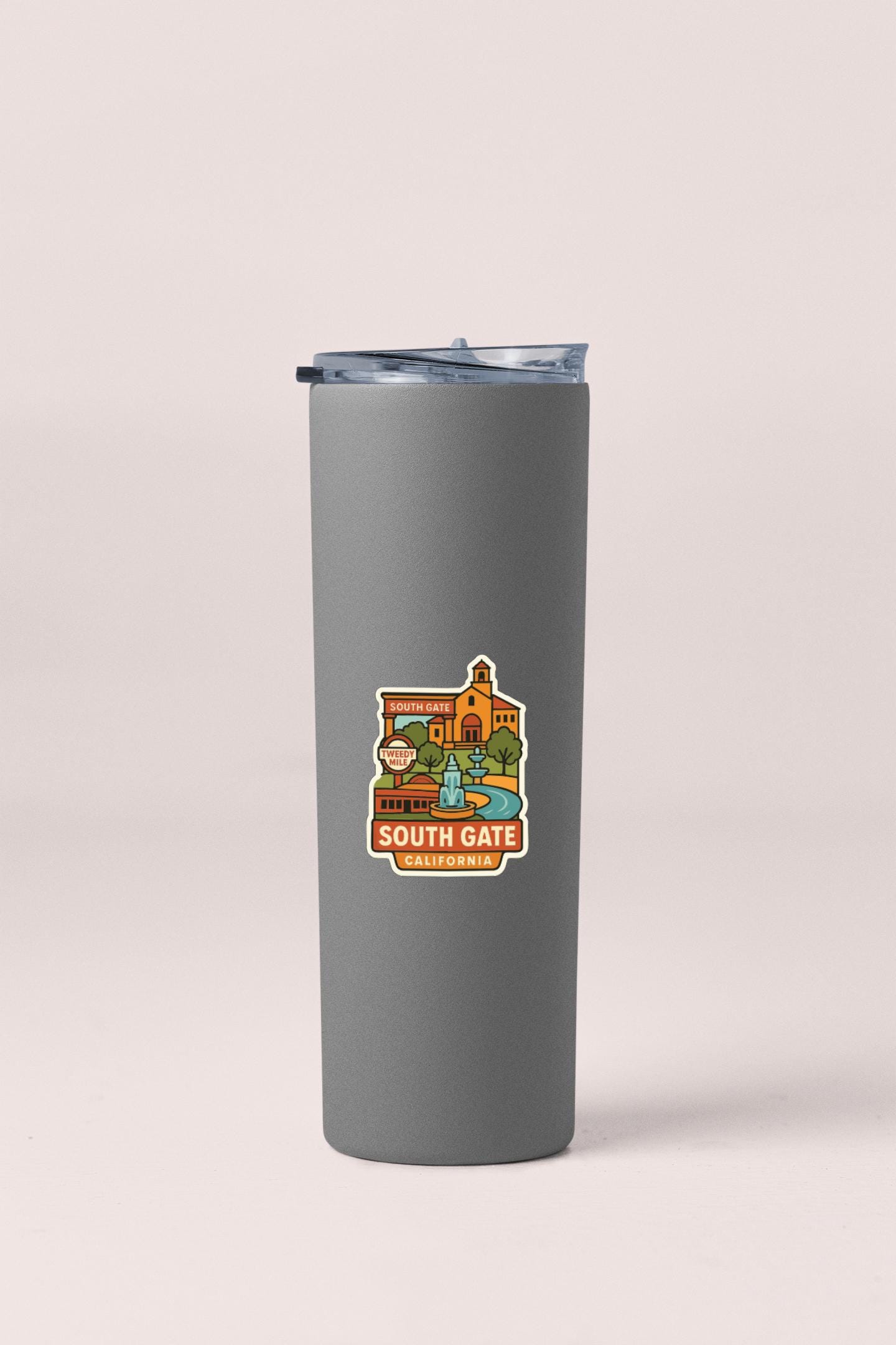 A gray insulated tumbler with a lid and a sticker depicting a cityscape with a building and a fountain.