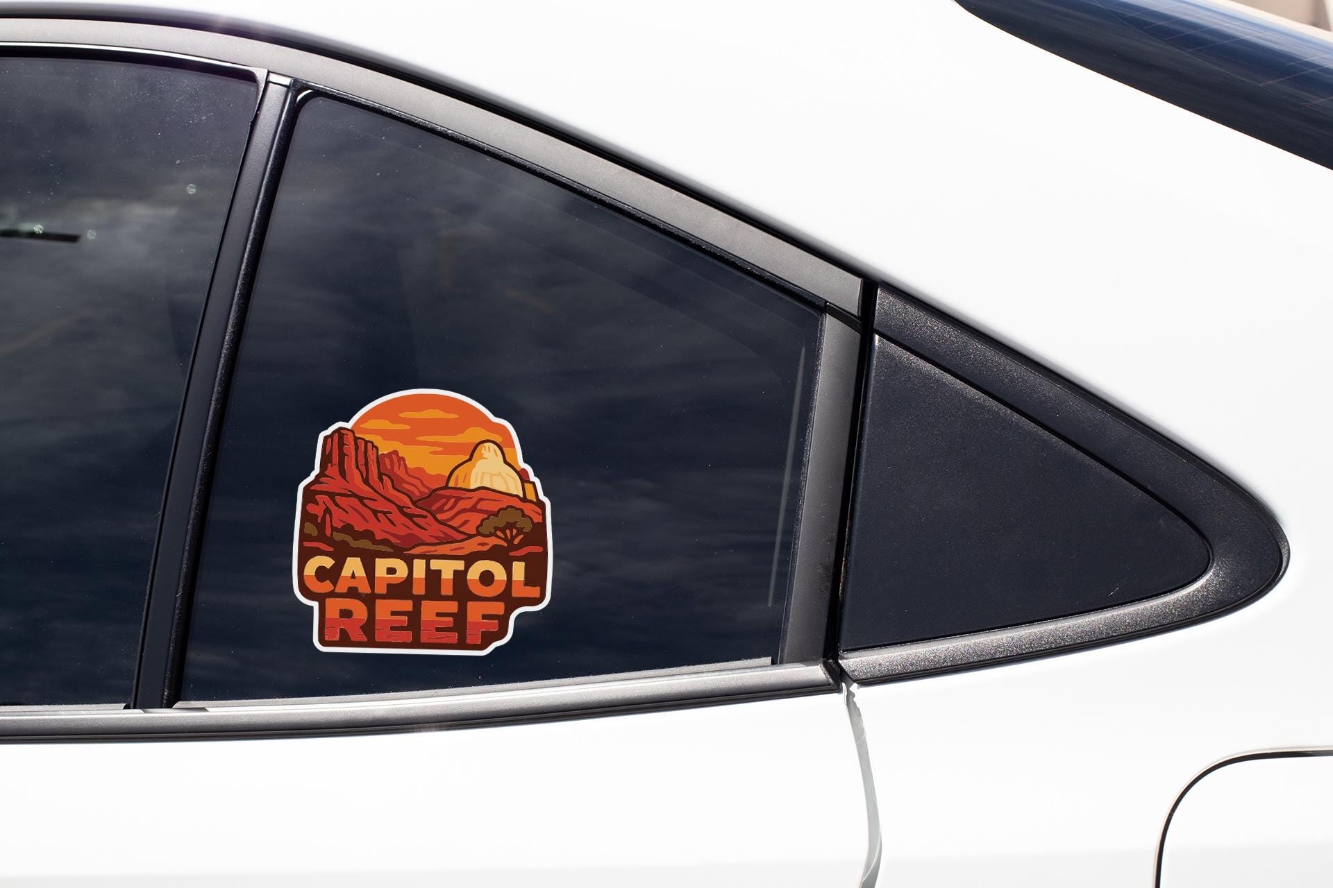 A car window with a sticker on it, featuring an illustration of a mountain range and the text "CAPITOL REEF".