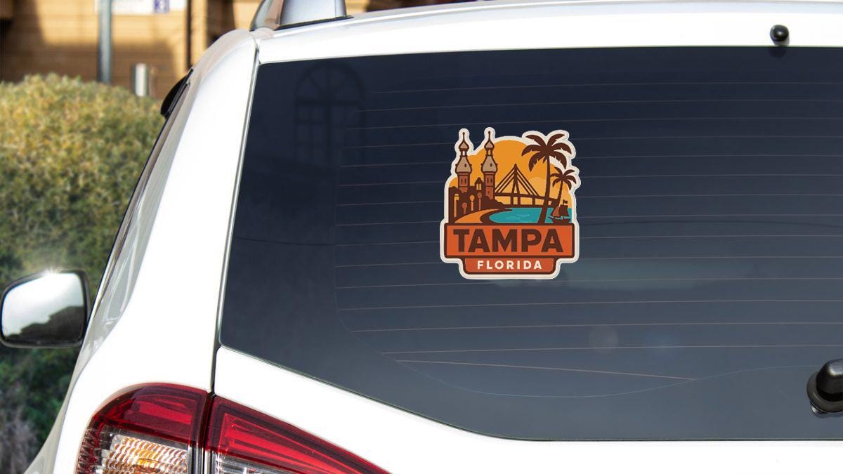 A sticker on the rear window of a white car, depicting a cityscape with palm trees and a bridge, along with the text "TAMPA FLORIDA".