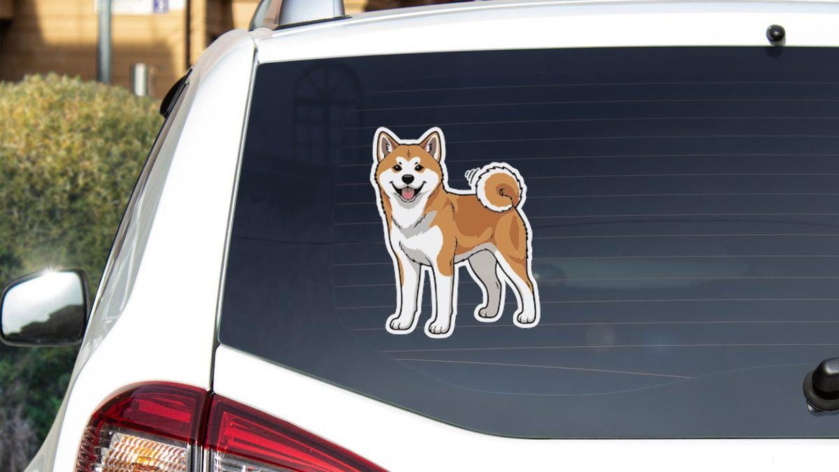 A sticker of a dog is on the rear window of a white car.