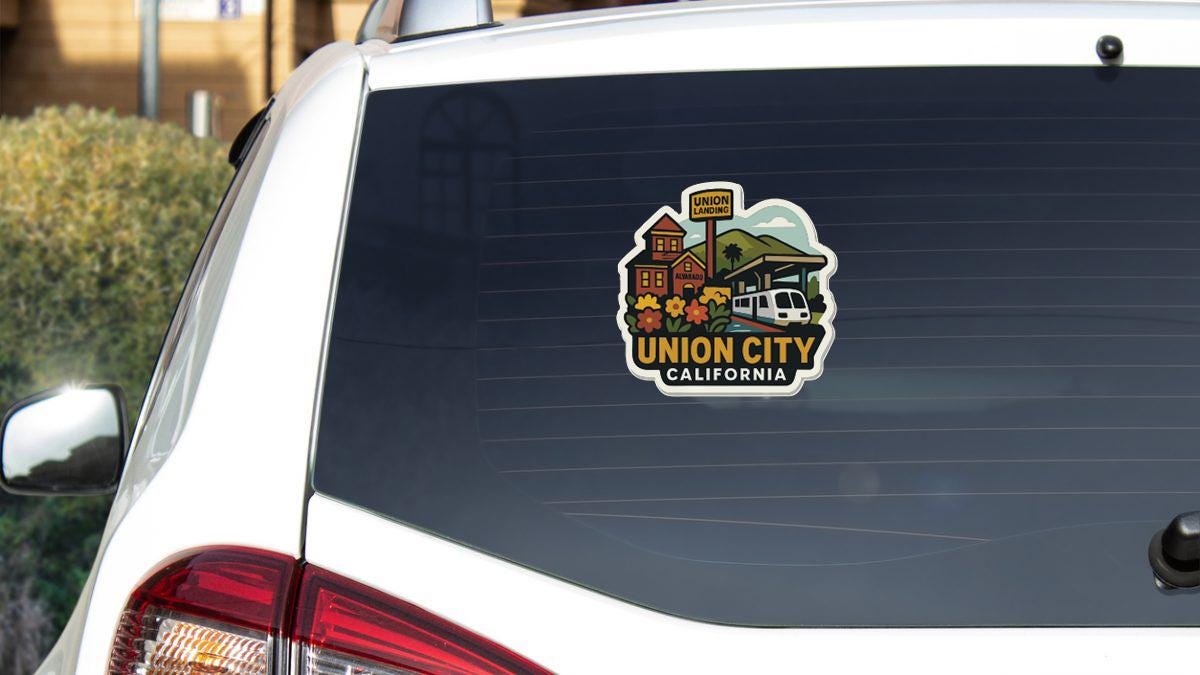 A sticker on the rear window of a white car, depicting a scenic view of Union City, California.