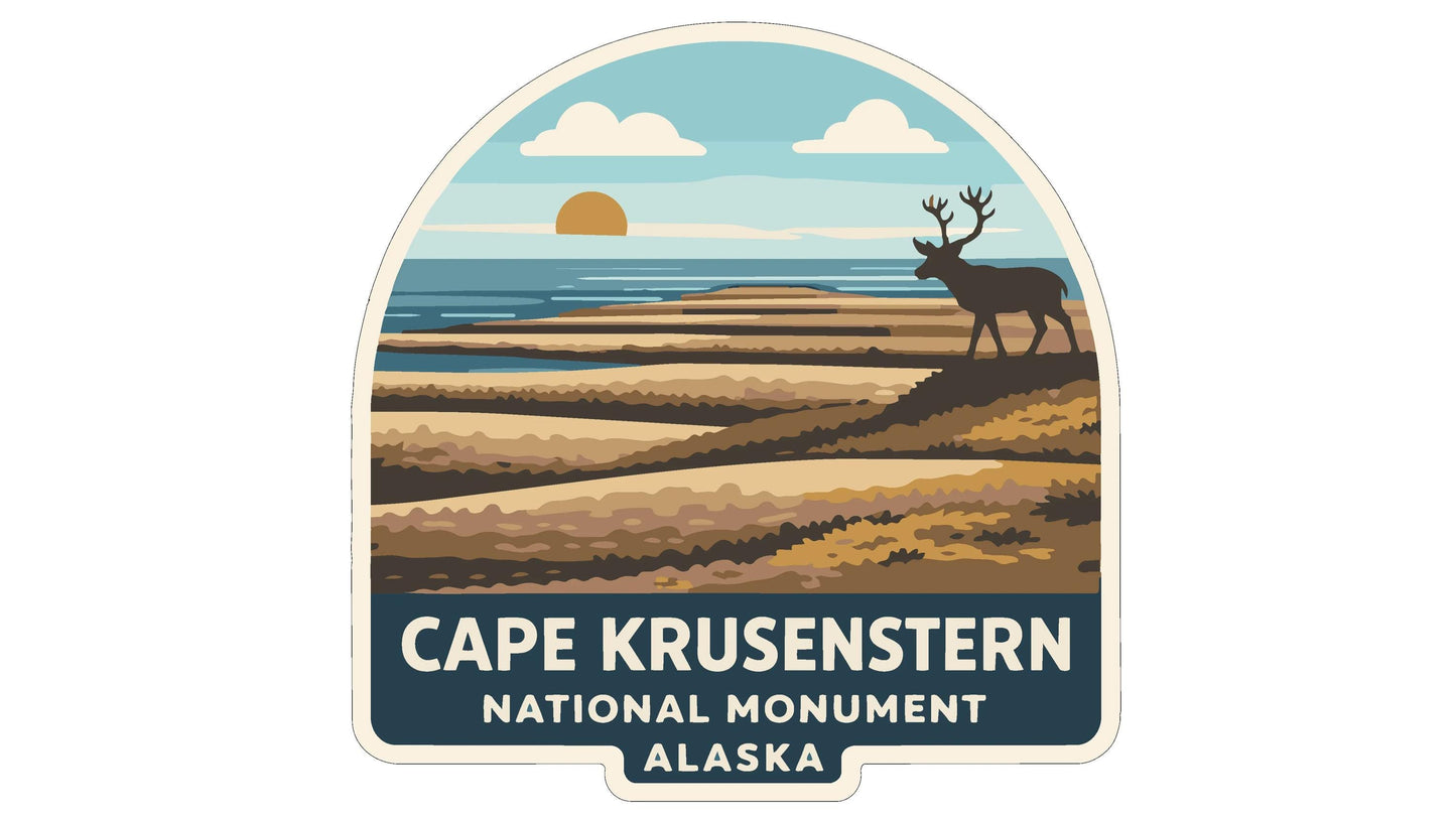 a sticker or emblem with a scenic landscape and a deer in the background, along with the text "CAPE KRUSENSTERN NATIONAL MONUMENT ALASKA".