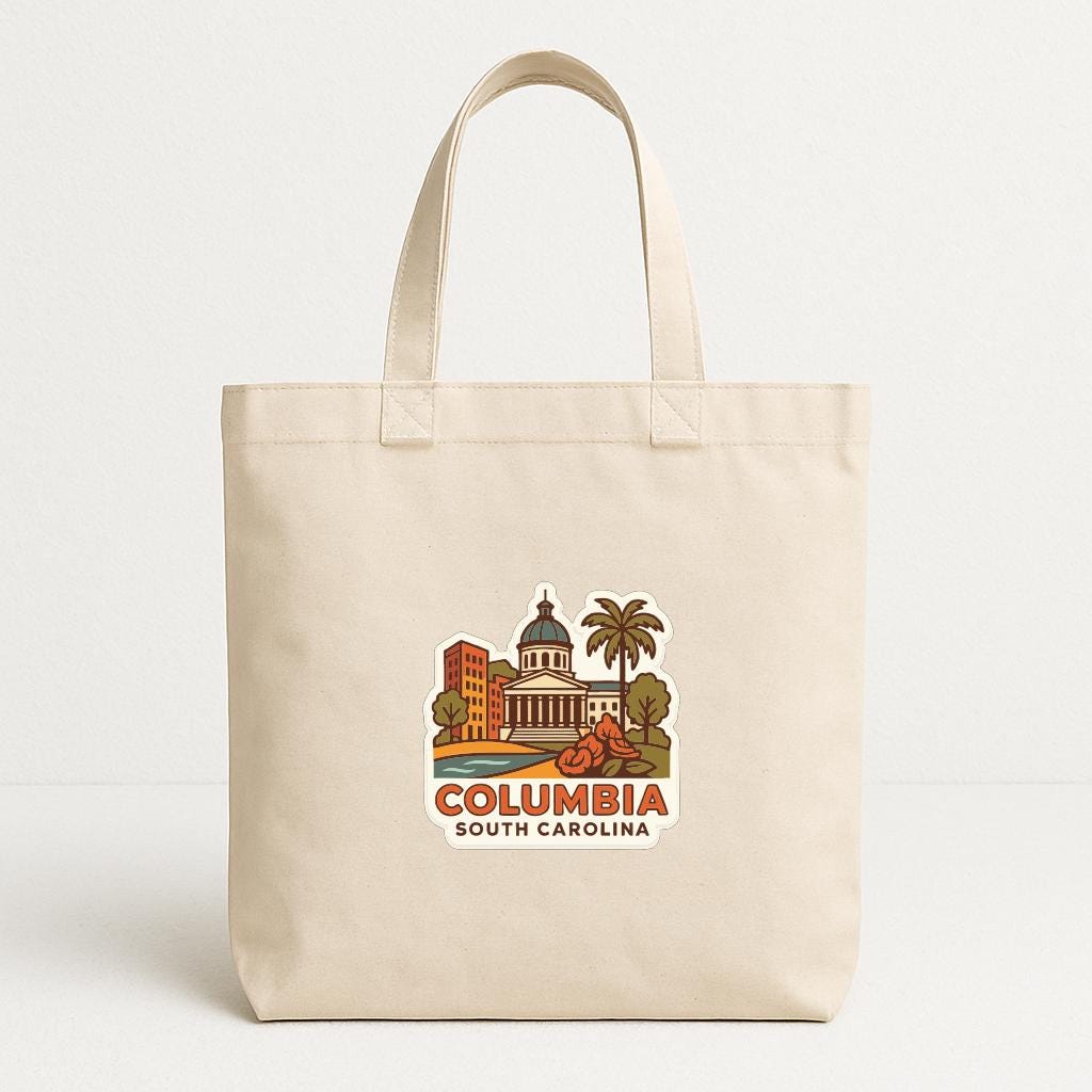 A beige tote bag with a printed design depicting a cityscape and the text "Columbia South Carolina" printed on it.