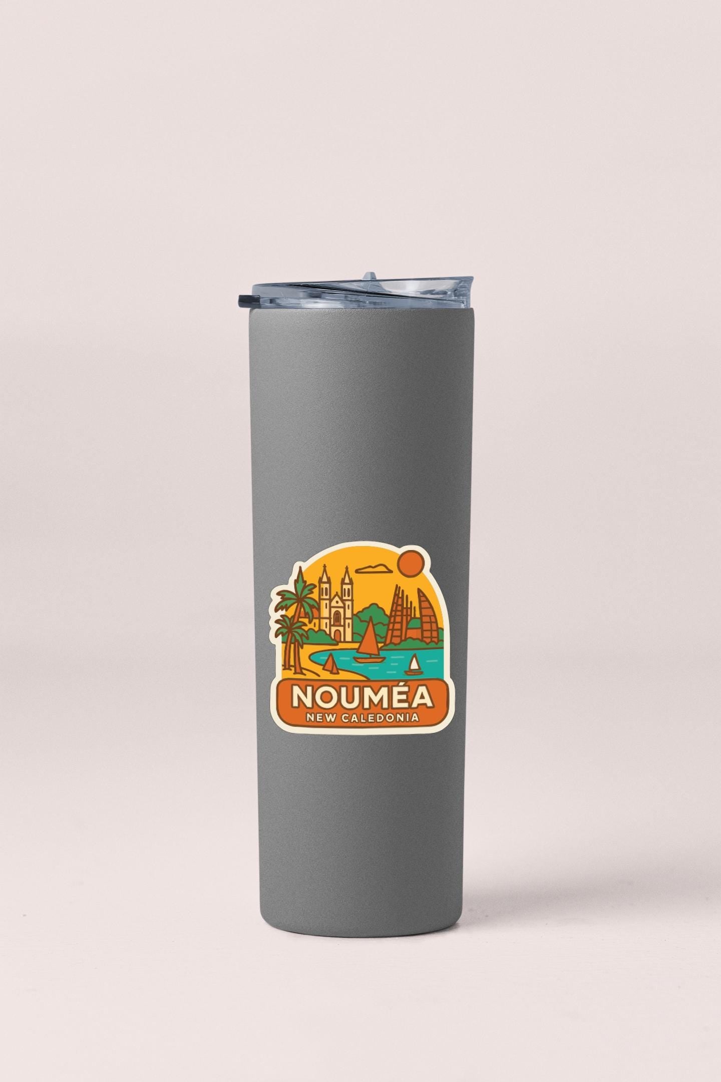 A gray insulated tumbler with a sticker depicting a scenic view of Noumea, New Caledonia.