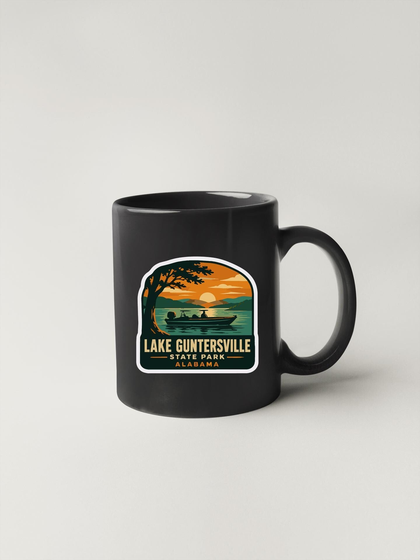 A black coffee mug with a sticker depicting a scenic lake and a boat on the water.