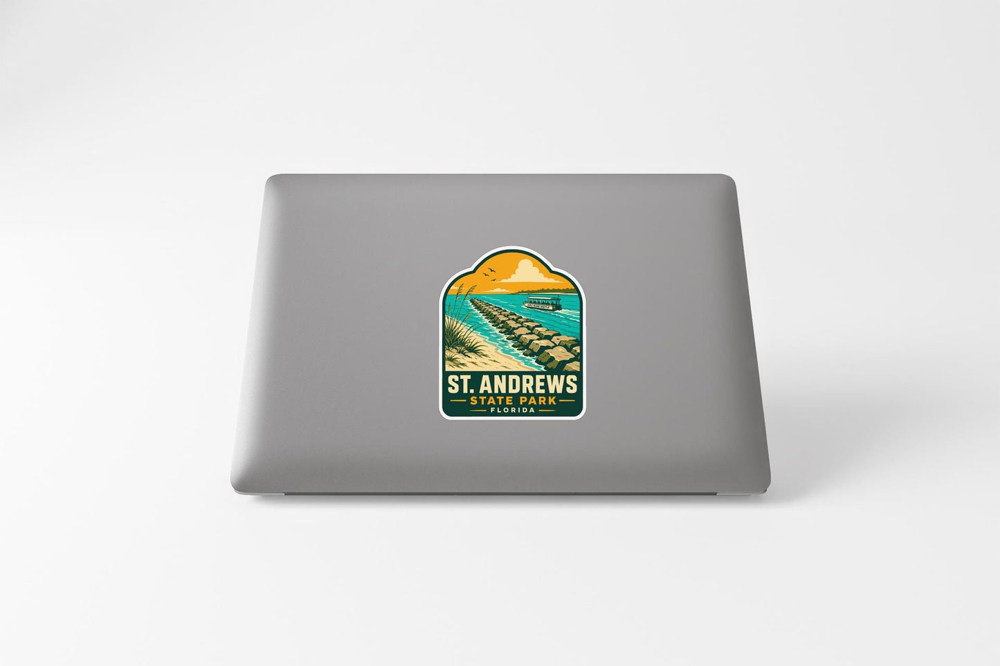 A sticker on the back of a laptop, depicting a scenic beach with palm trees and a sunset.