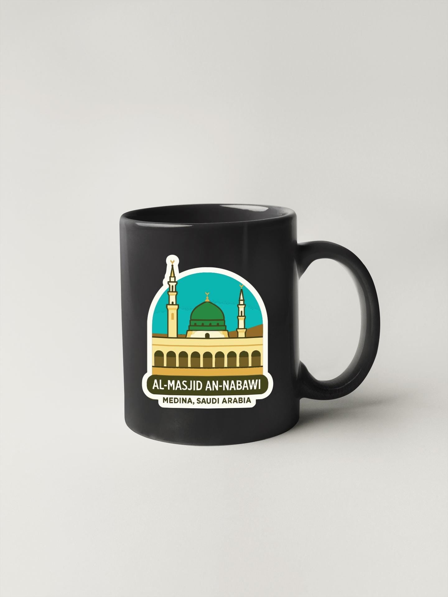 A black coffee mug with a graphic design depicting the Al-Majid Al-Nabawi Mosque in Saudi Arabia.