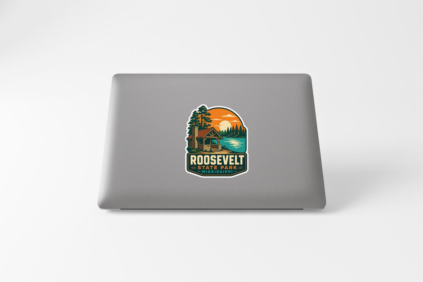 a sticker with a scenic landscape and a cabin, placed on the back of a laptop.