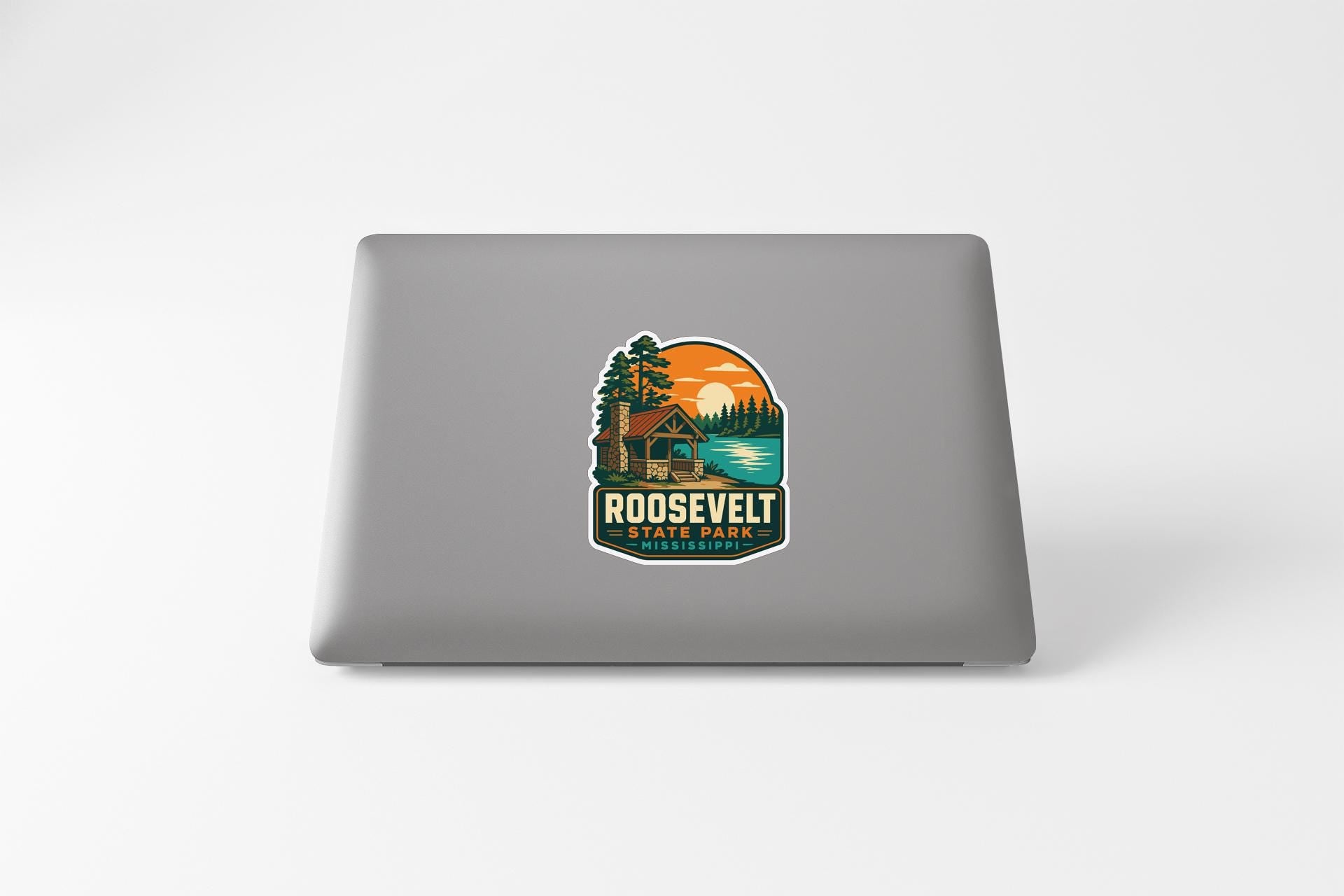 a sticker with a scenic landscape and a cabin, placed on the back of a laptop.