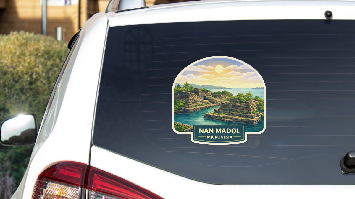 A sticker on the rear window of a car, depicting a scenic landscape with mountains, water, and a sunset.
