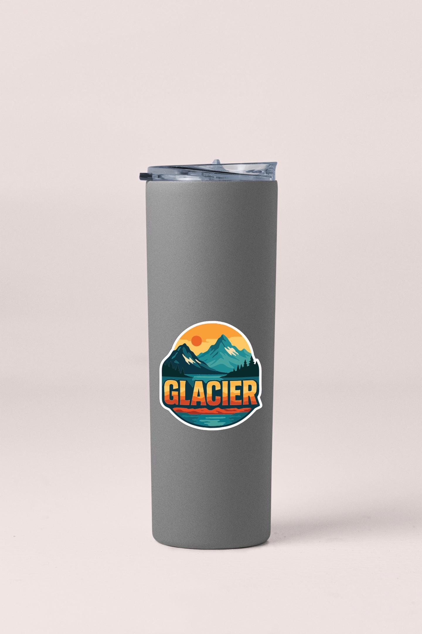 A gray insulated tumbler with a sticker depicting a mountain landscape and the word "GLACIER" printed on it.