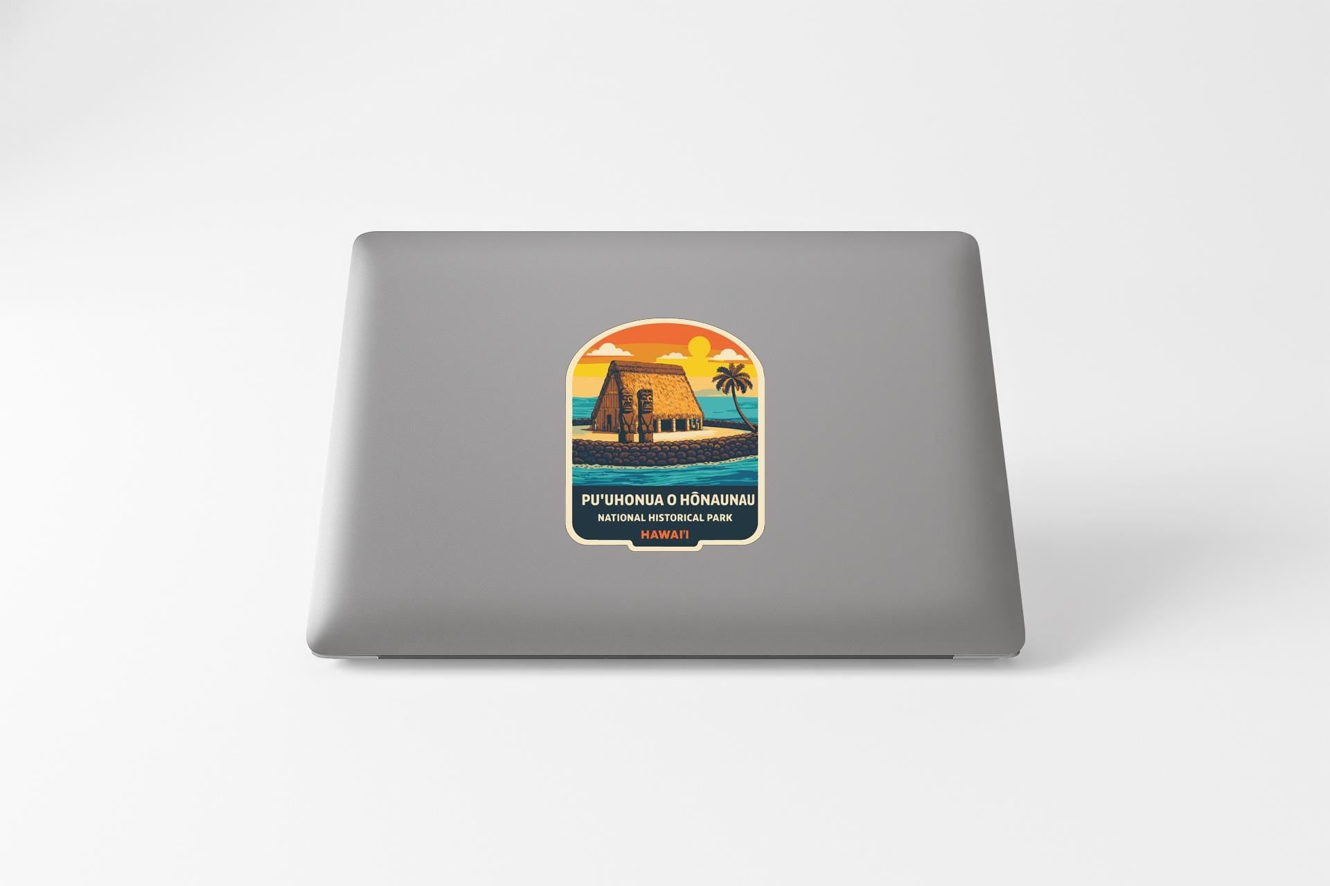 a sticker on the back of a laptop with a tropical beach scene and a house.