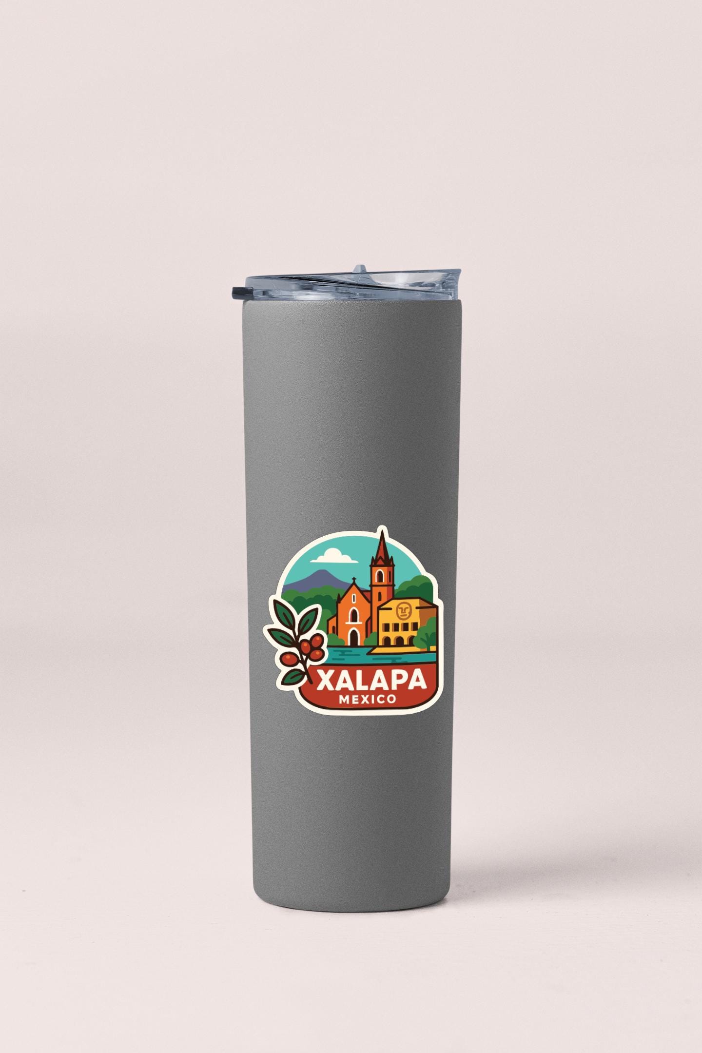 A gray insulated tumbler with a sticker depicting a cityscape and the text "XALAPA MEXICO" printed on it.
