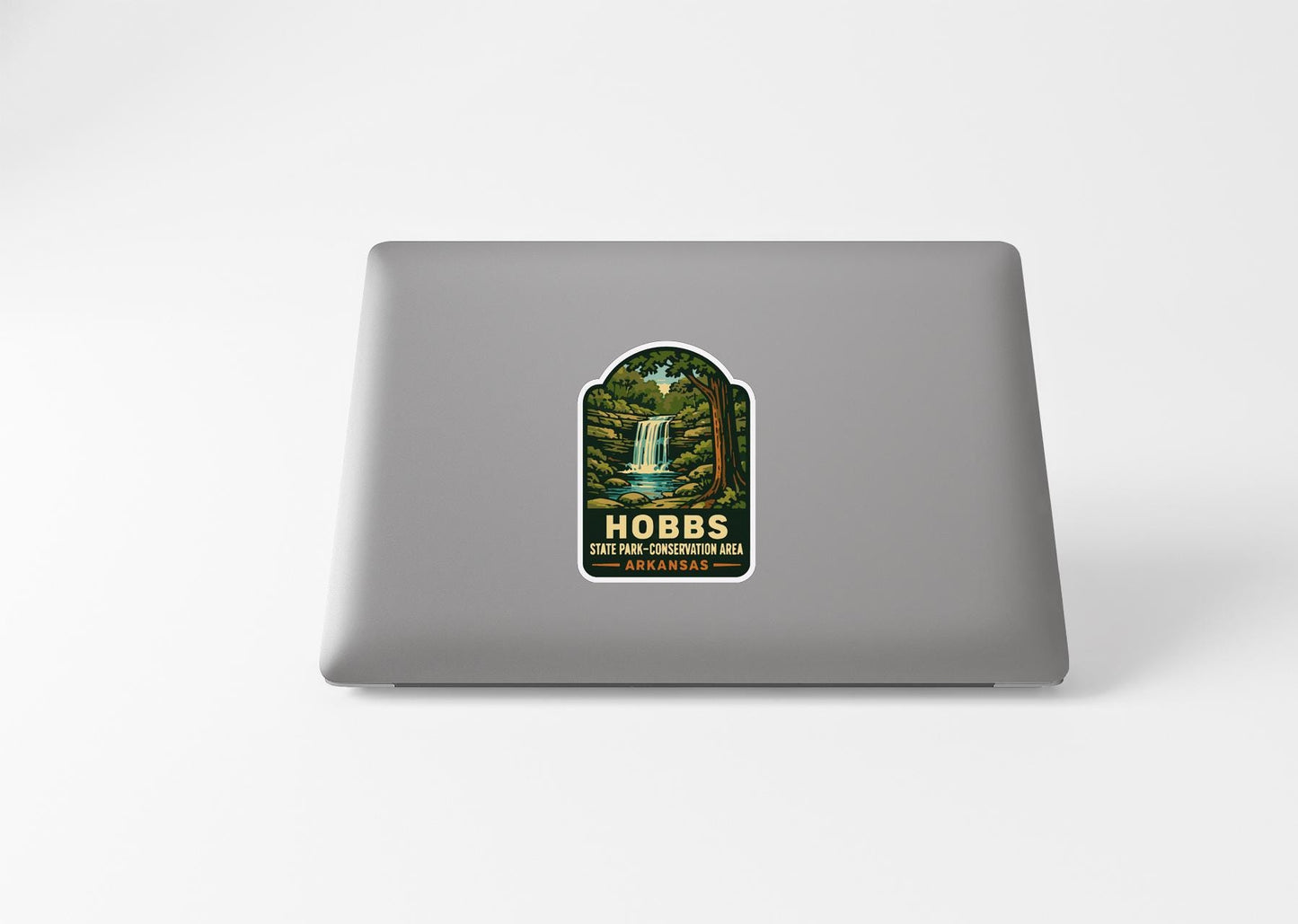 A sticker with a waterfall and forest on a laptop.