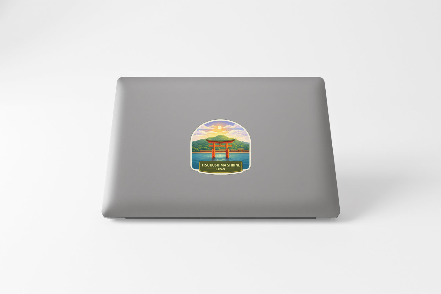 A sticker depicting a scenic landscape with a temple in the background, placed on the back of a laptop computer.