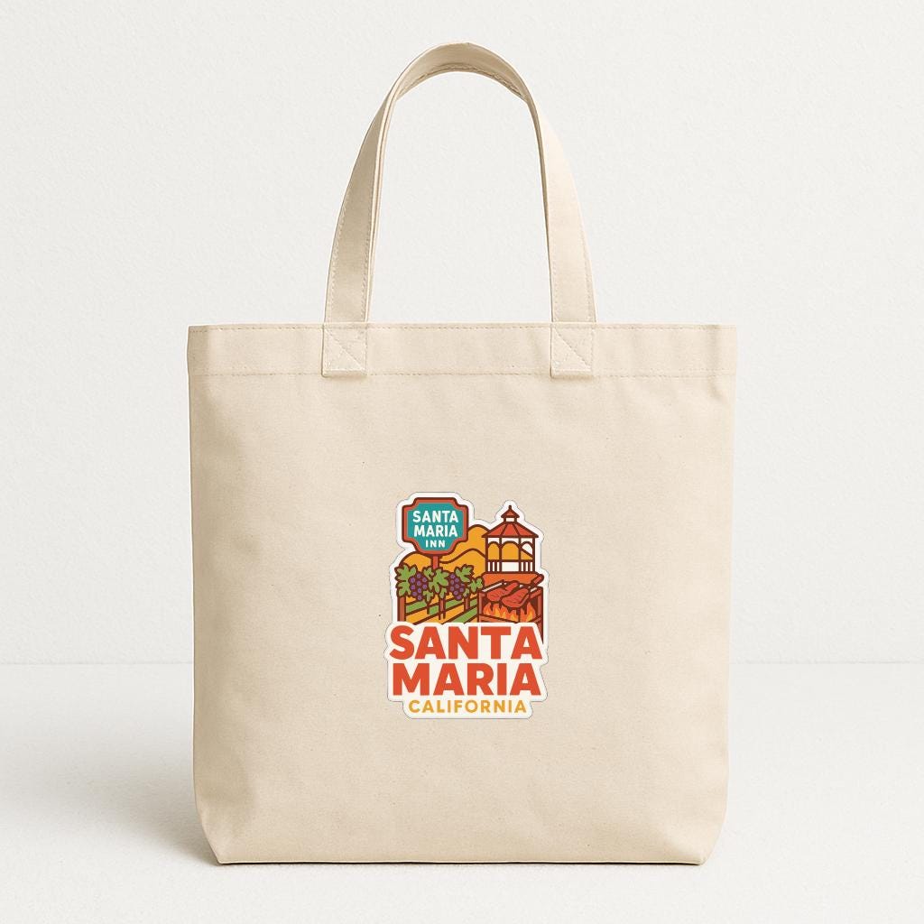 A beige tote bag with a printed design of Santa Maria, California, featuring a colorful illustration of a building and palm trees.