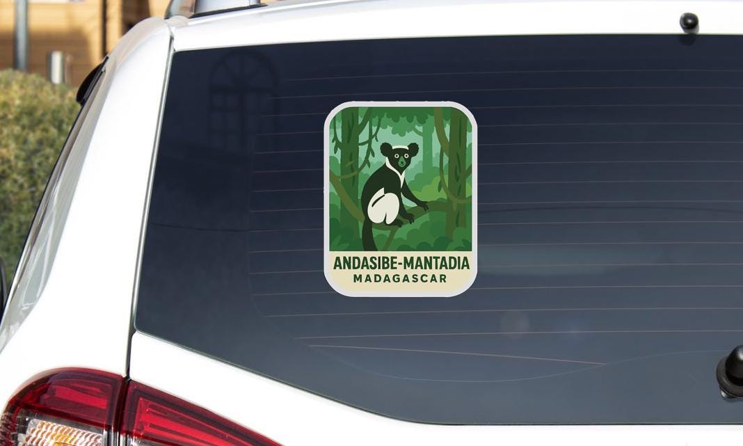 A sticker on the rear window of a car, depicting a lemur in a forest setting.