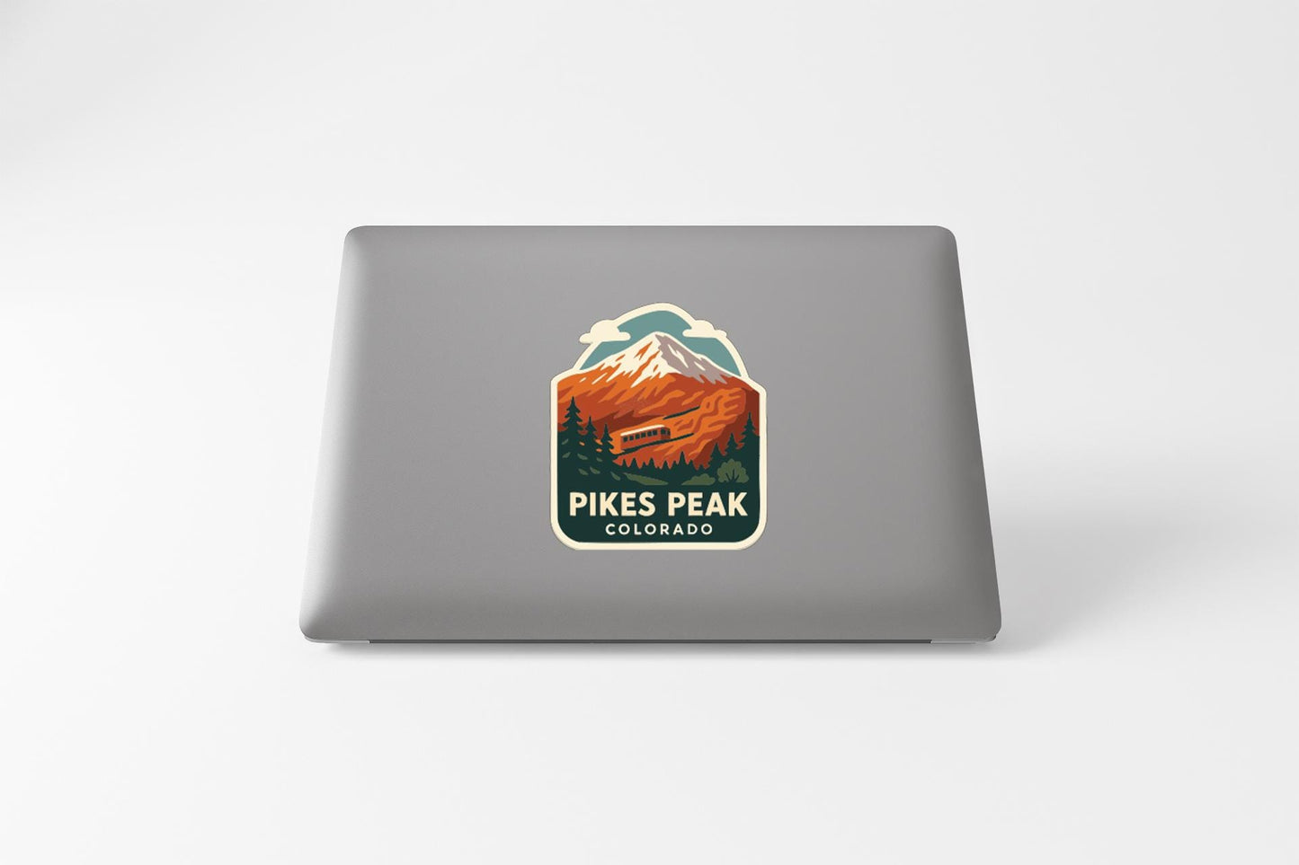 A sticker on the back of a laptop that features a mountain landscape with a ski lift, along with the text "Pikes Peak, Colorado".