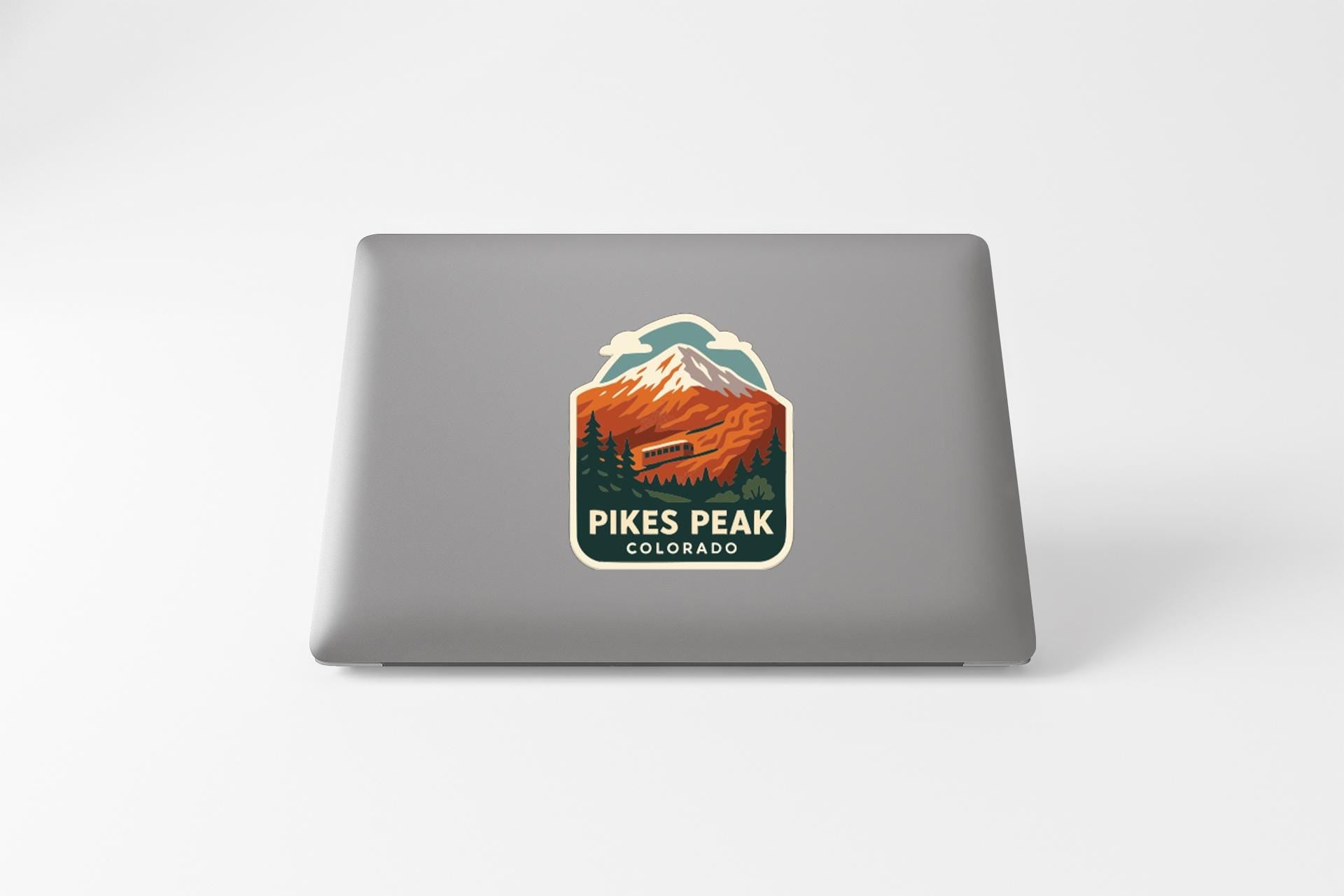 A sticker on the back of a laptop that features a mountain landscape with a ski lift, along with the text "Pikes Peak, Colorado".