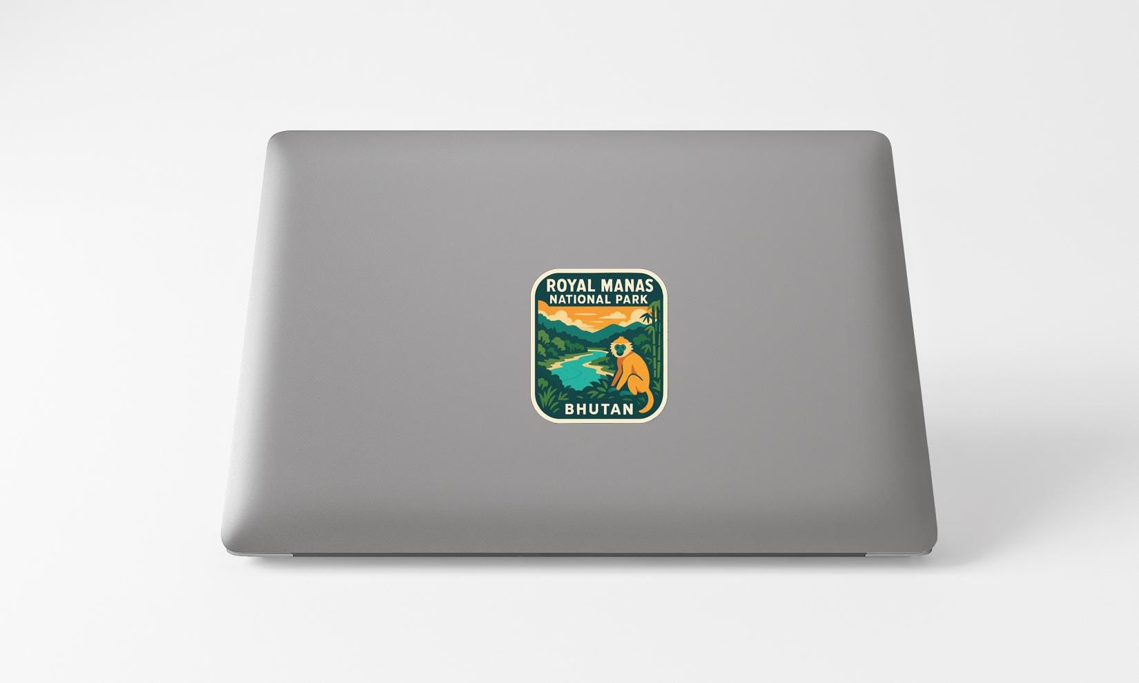 A sticker on the back of a laptop, depicting a scenic landscape with mountains and a river.
