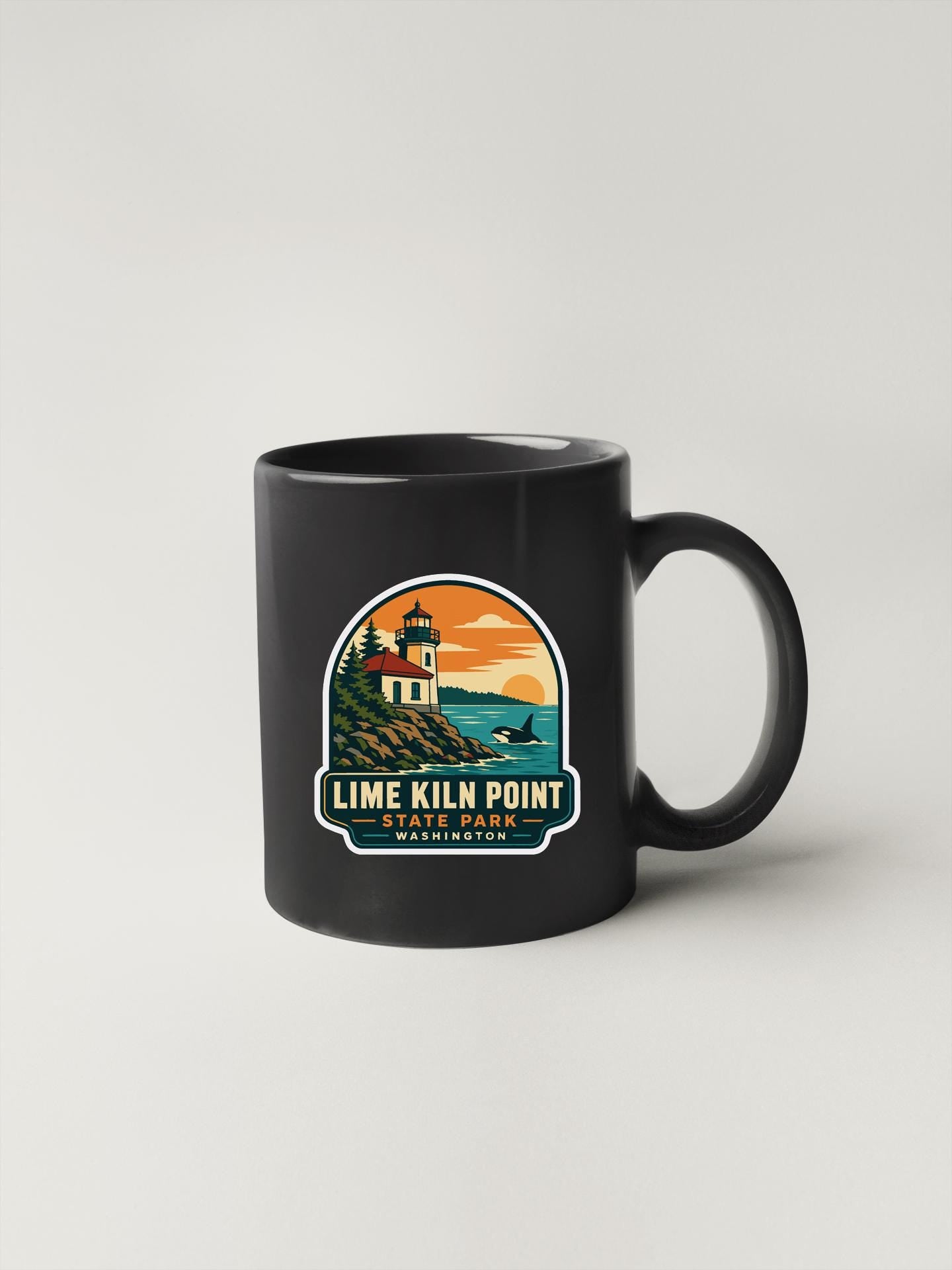 A black coffee mug with a graphic design depicting a lighthouse and a sunset over the ocean.