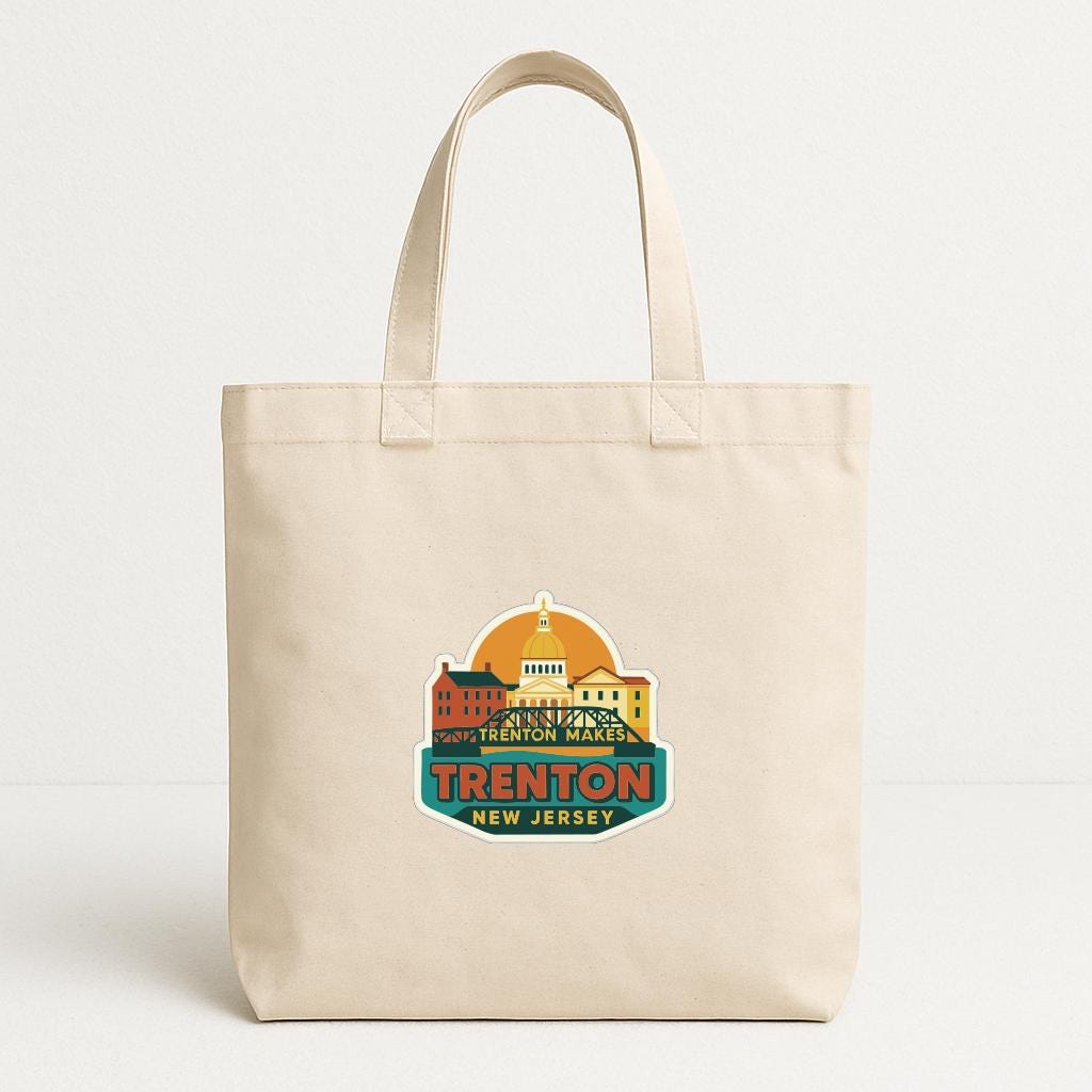 A beige tote bag with a colorful graphic design featuring a city skyline and the text "Trenton, New Jersey".