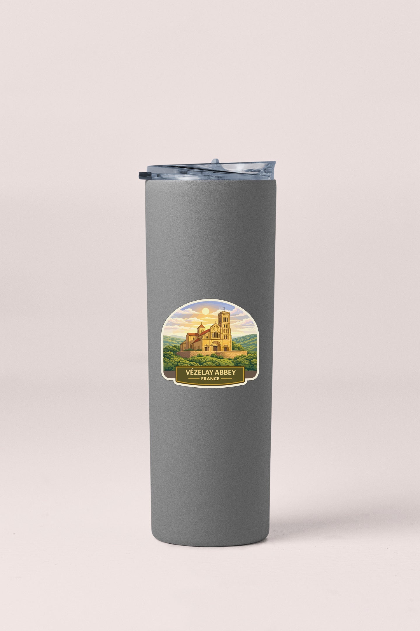 A gray insulated tumbler with a label that features an illustration of a castle and the text "Vezilay Abbey France".