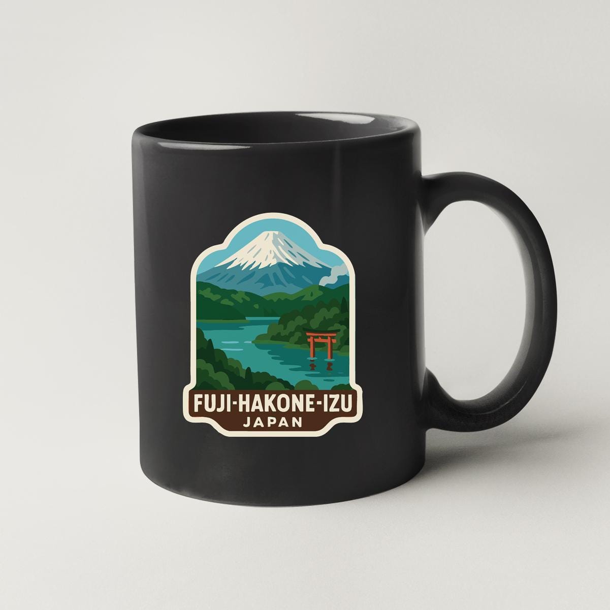 A black coffee mug with a sticker depicting the famous Mount Fuji and the Shinto shrine in Japan.