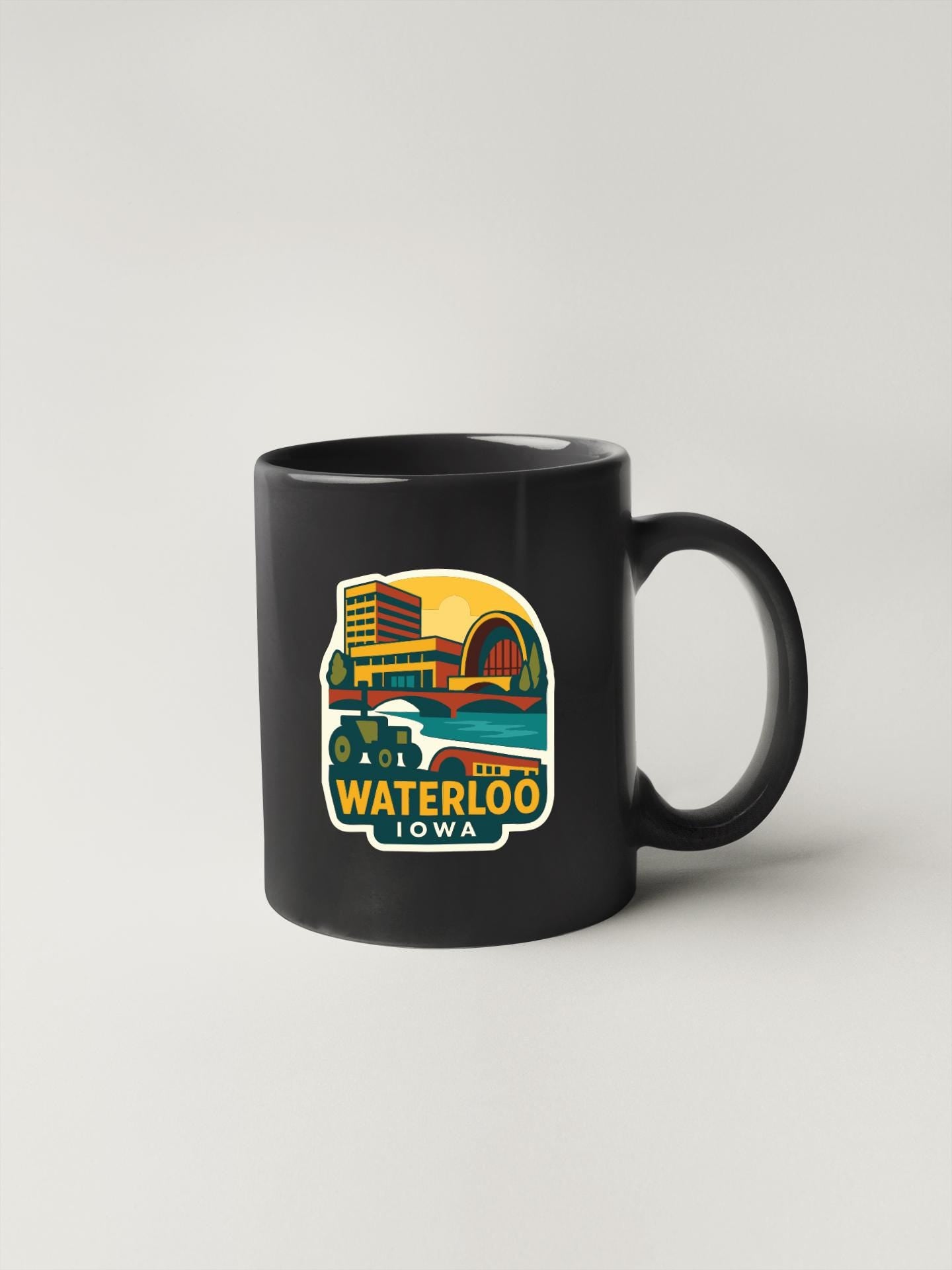 A black coffee mug with a colorful graphic depicting a cityscape and the text "WATERLOO IOWA" printed on it.