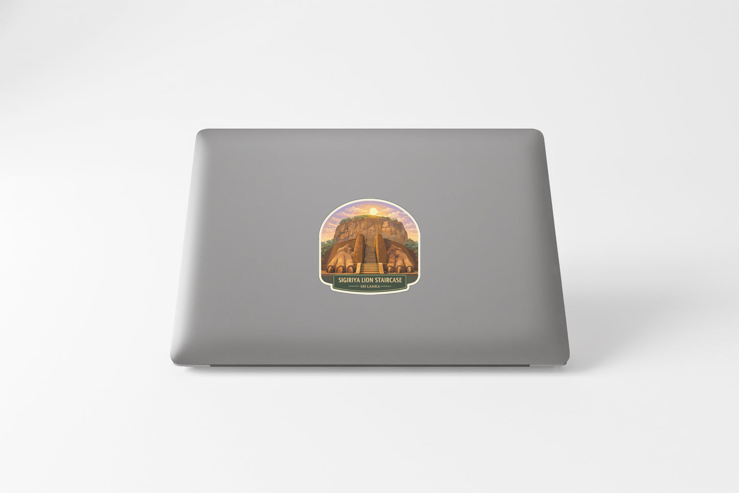 a sticker on the back of a laptop, depicting a building or structure with a sunset in the background.