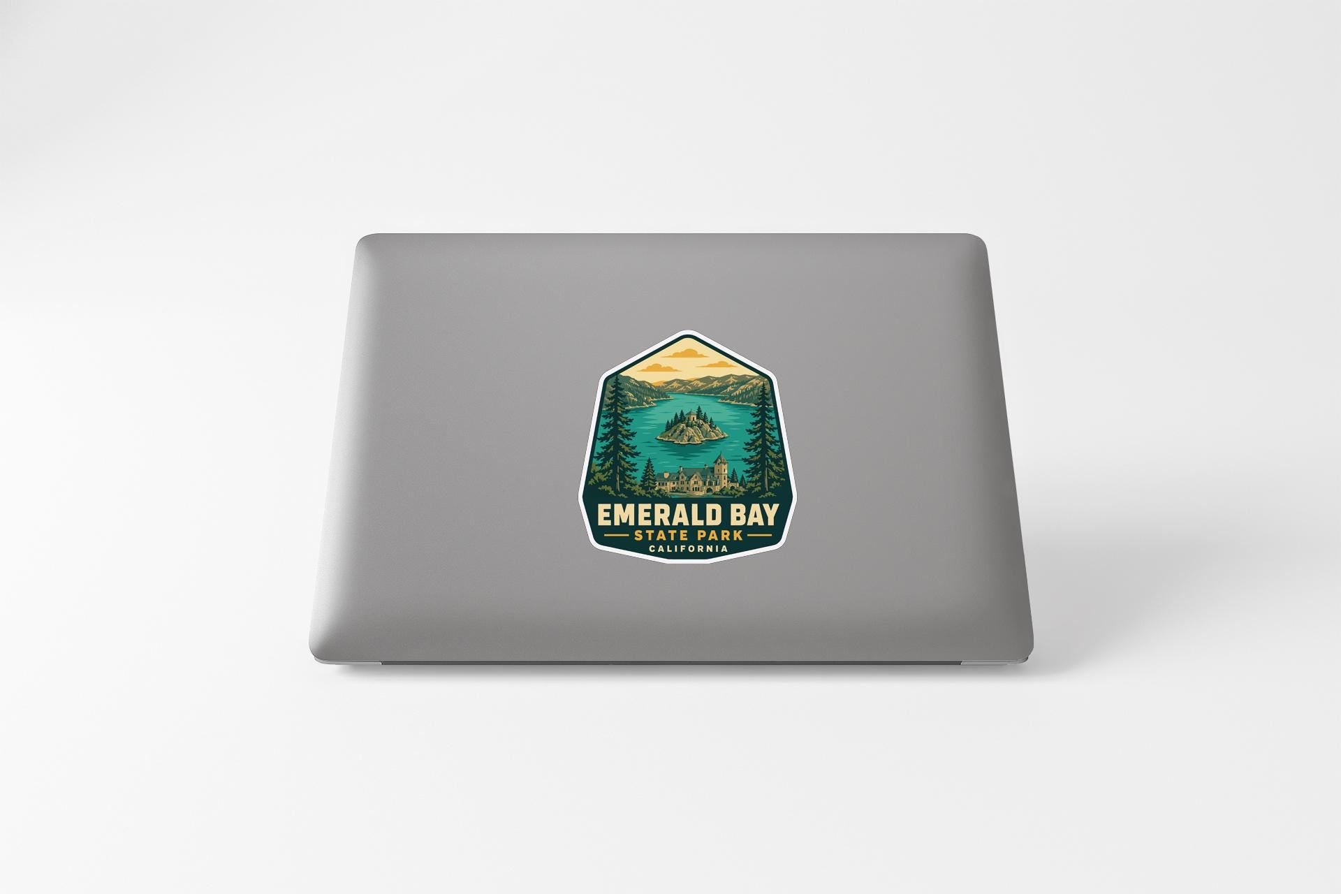 A sticker on the back of a laptop, depicting a scenic landscape with a lake and mountains.