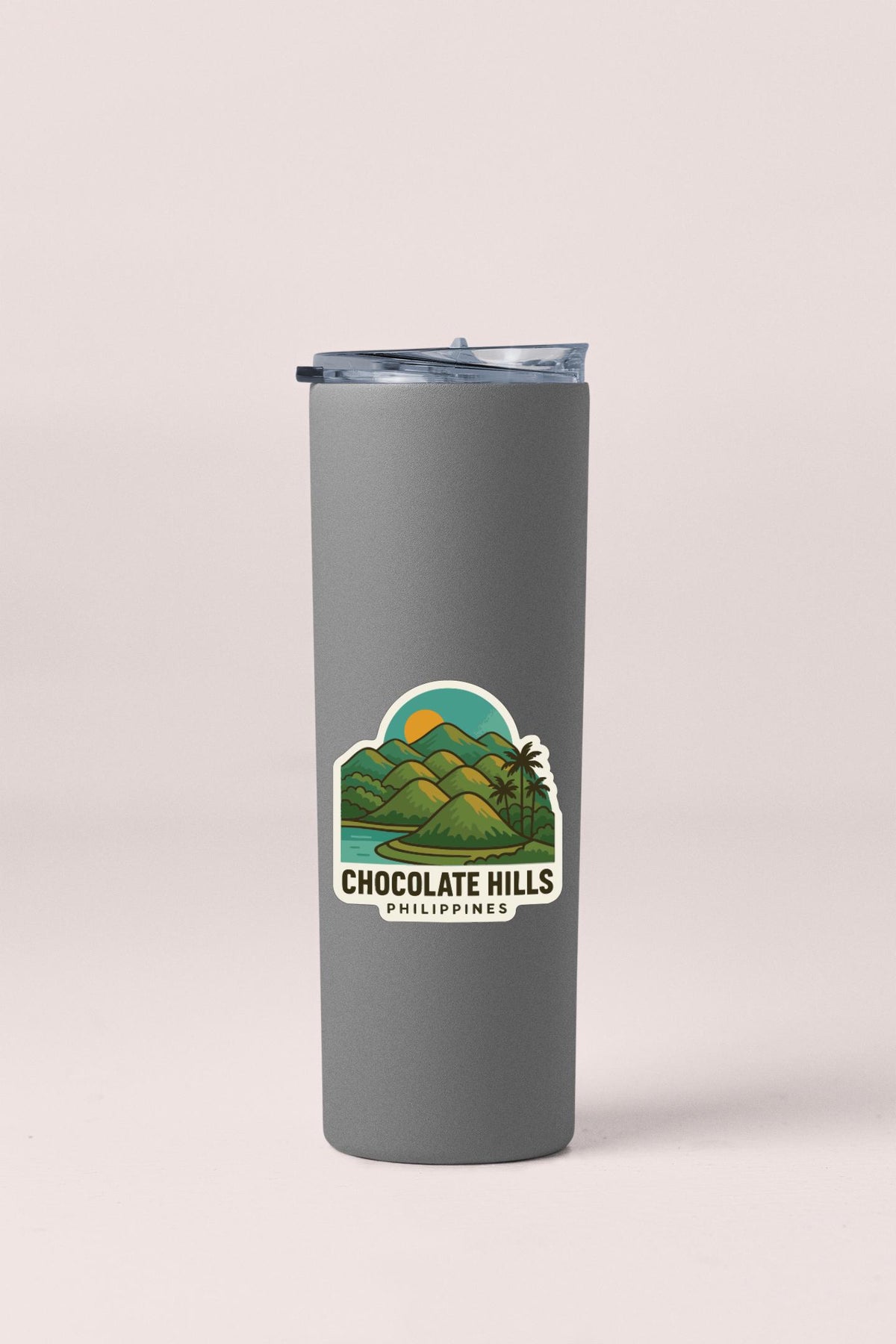 A gray insulated tumbler with a sticker depicting a tropical landscape and the text "CHOCOLATE HILLS PHILIPPINES".