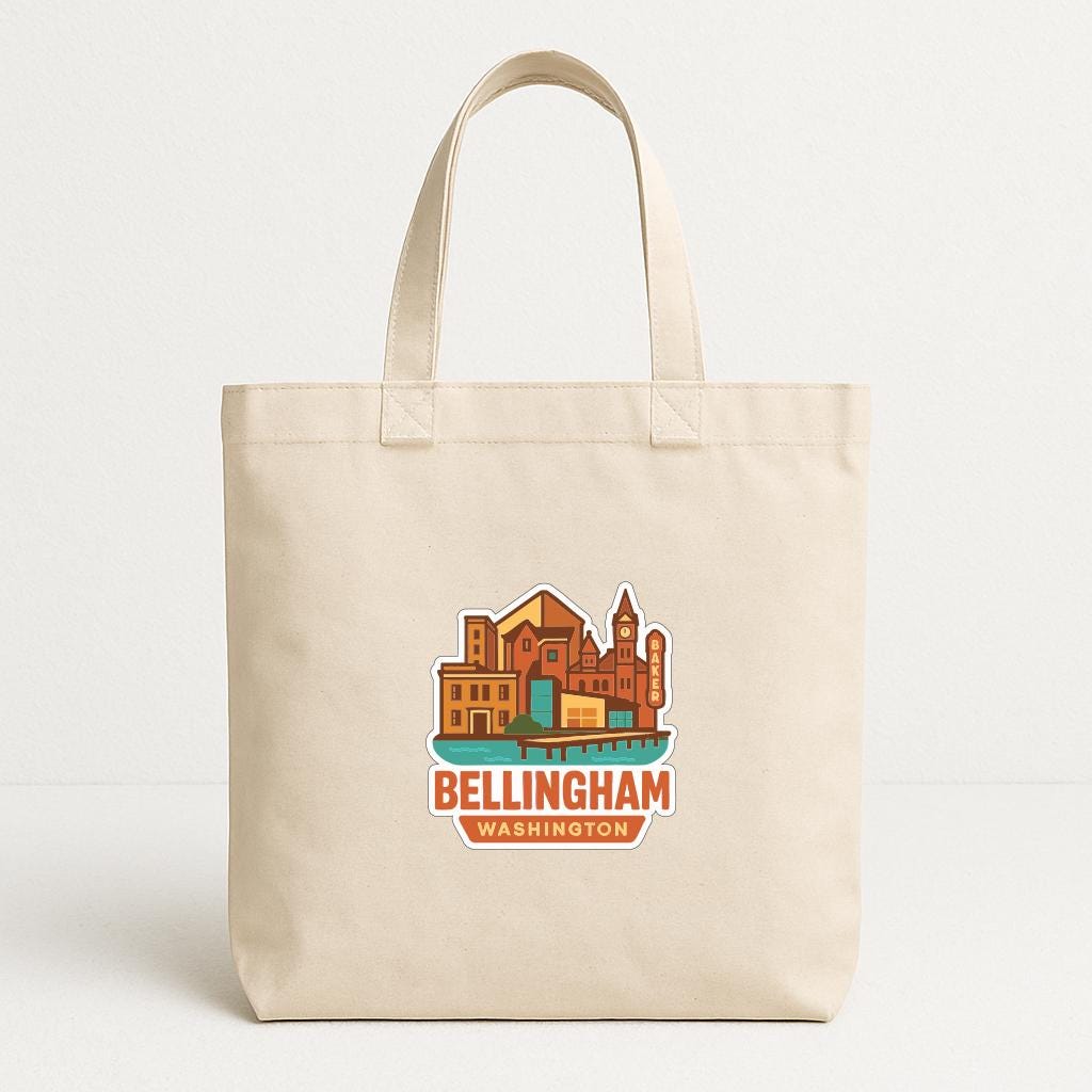 A beige tote bag with a printed design of a cityscape and the text "Bellingham Washington" printed on it.