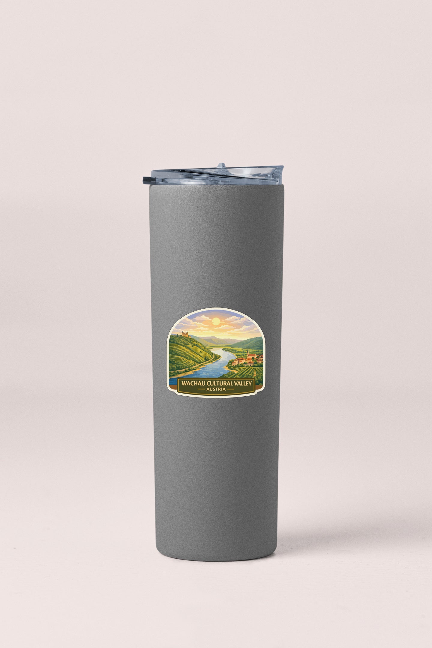 A gray insulated tumbler with a label depicting a scenic landscape.