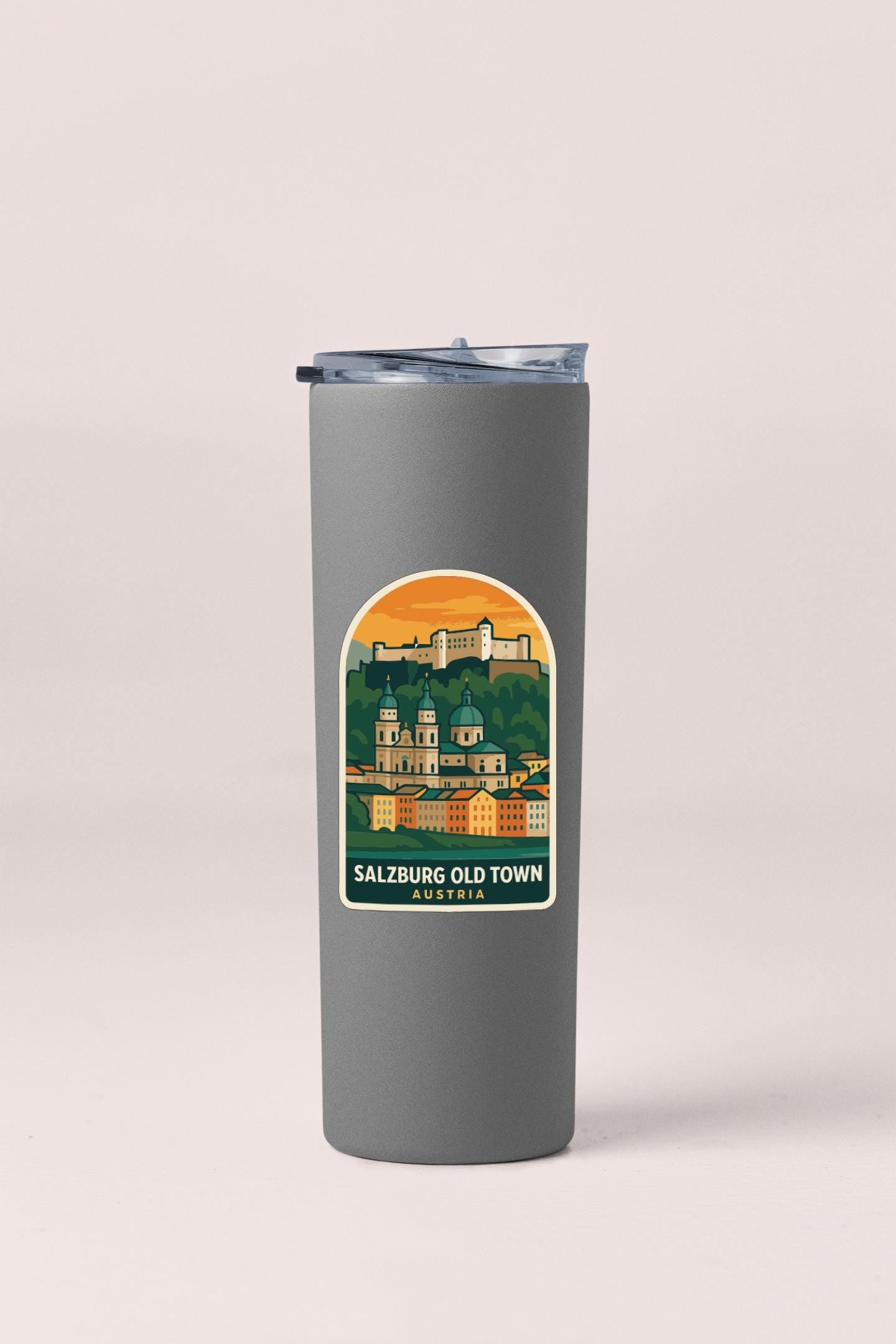 A gray insulated tumbler with a sticker depicting the Salzburg Old Town in Austria.