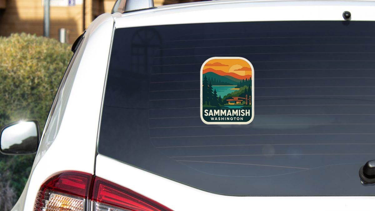 the rear window of a white car with a sticker on it, featuring a scenic landscape with mountains and a lake.